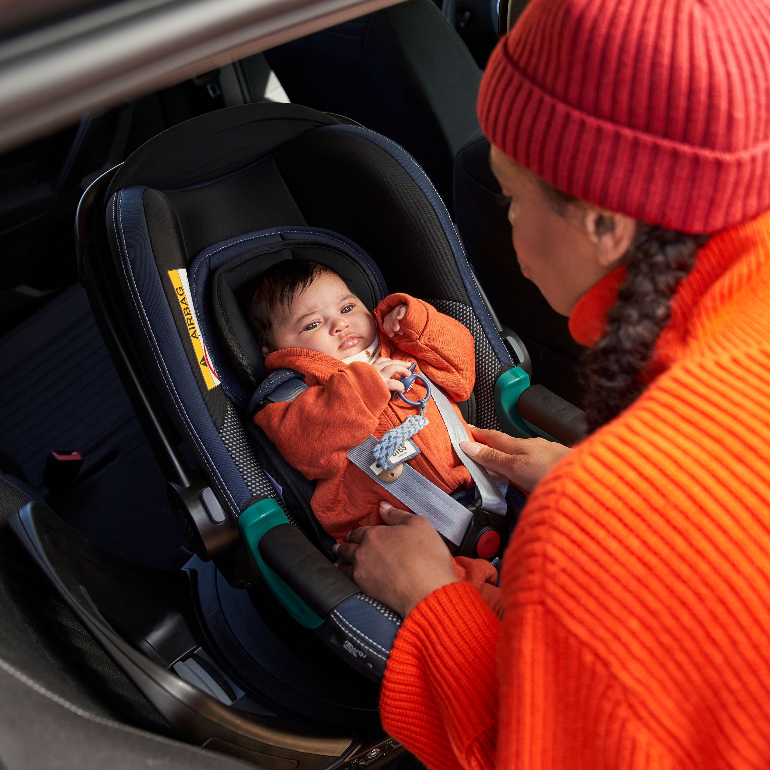 Žena pripína dieťa, ktoré sedí v detskej sedačke VW príslušenstva