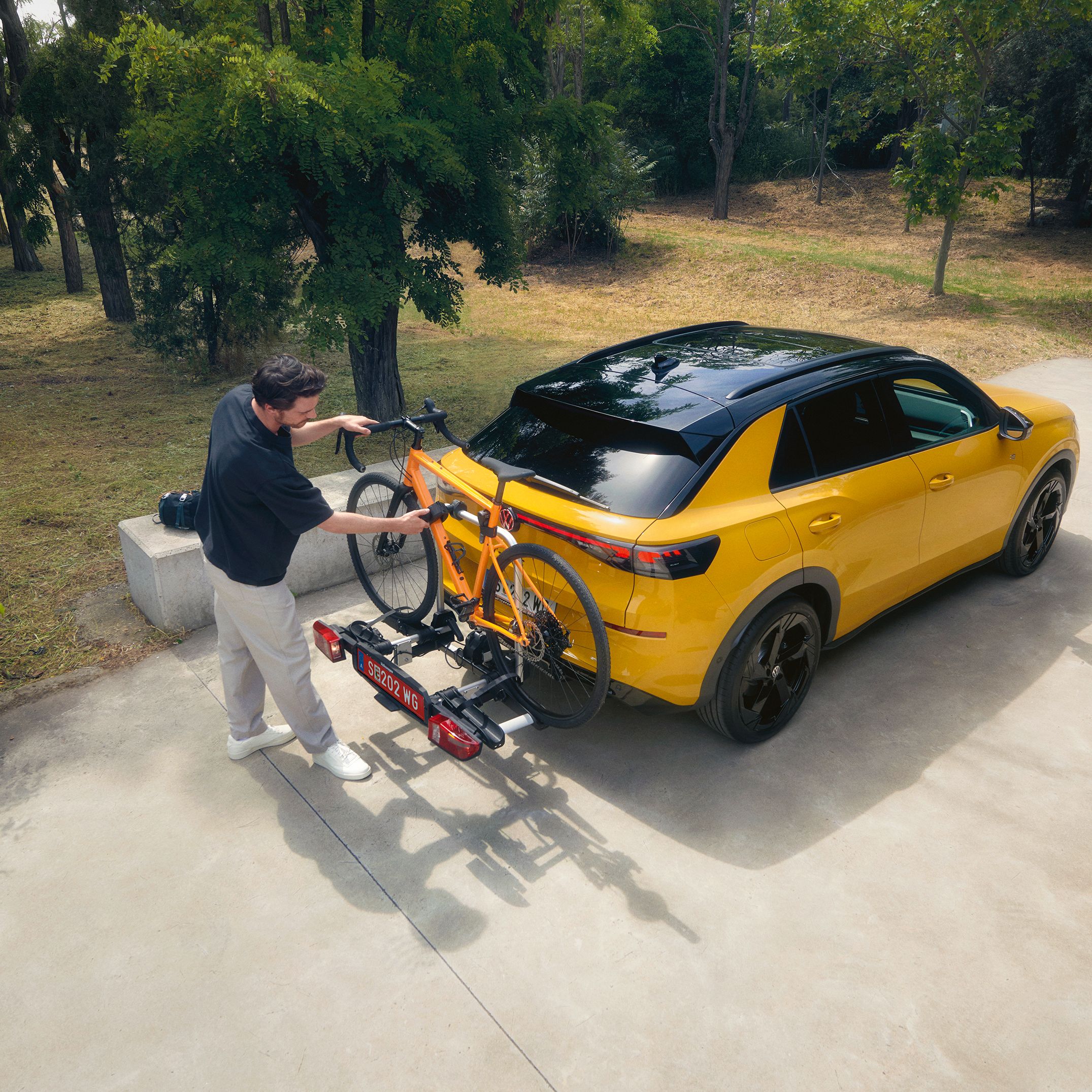 Muž pripevňuje bicykel na nosič bicyklov vozidla VW T-Roc R-Line.