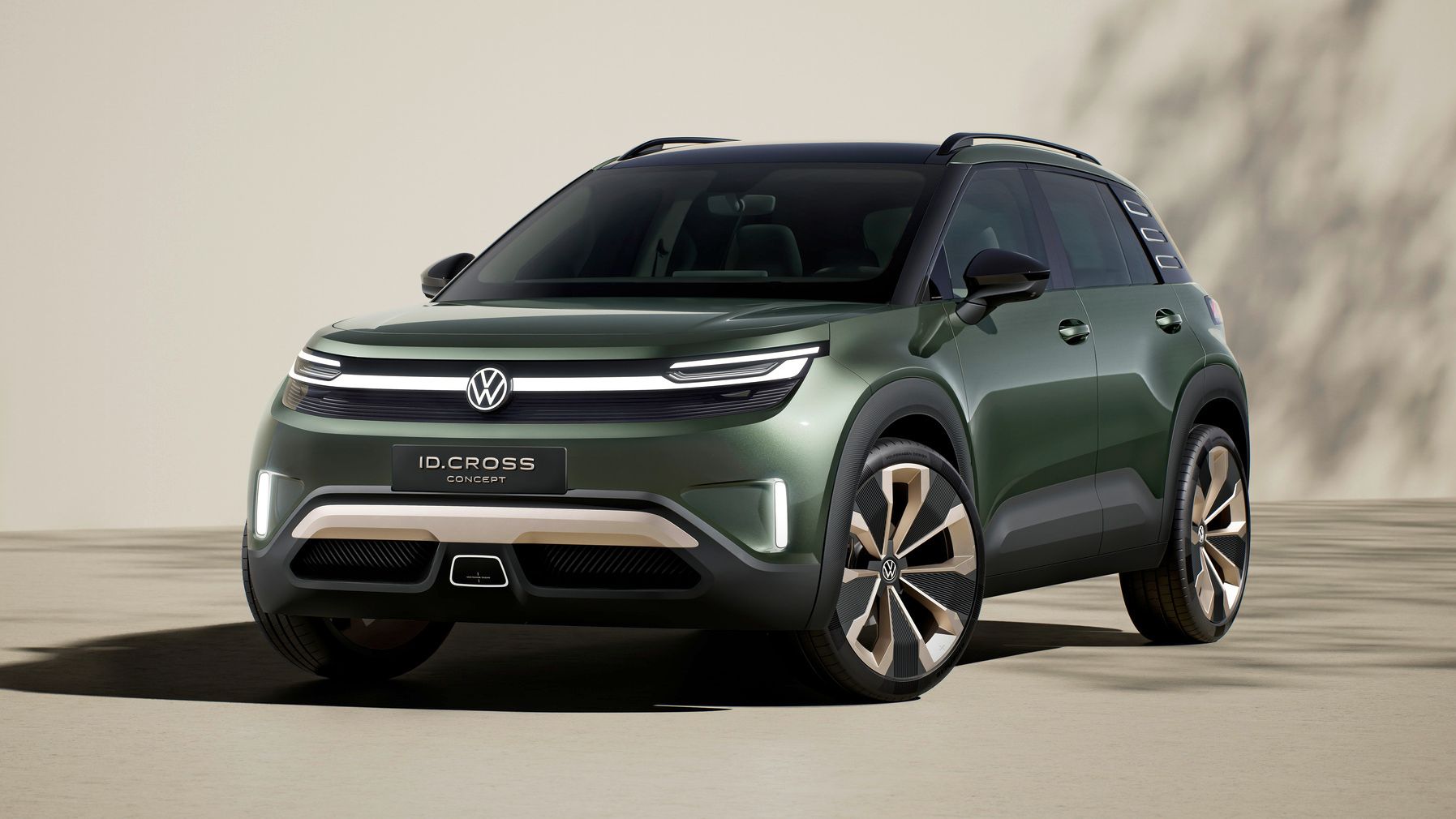 Volkswagen ID. Cross stojí na svetlom povrchu pred krémovou stenou a v pozadí vidieť tieň stromu. Model je štúdiou koncernu.