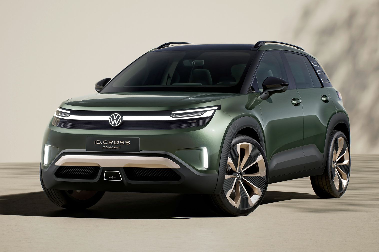 Volkswagen ID. Cross stojí na svetlom povrchu pred krémovou stenou a v pozadí vidieť tieň stromu. Model je štúdiou koncernu.