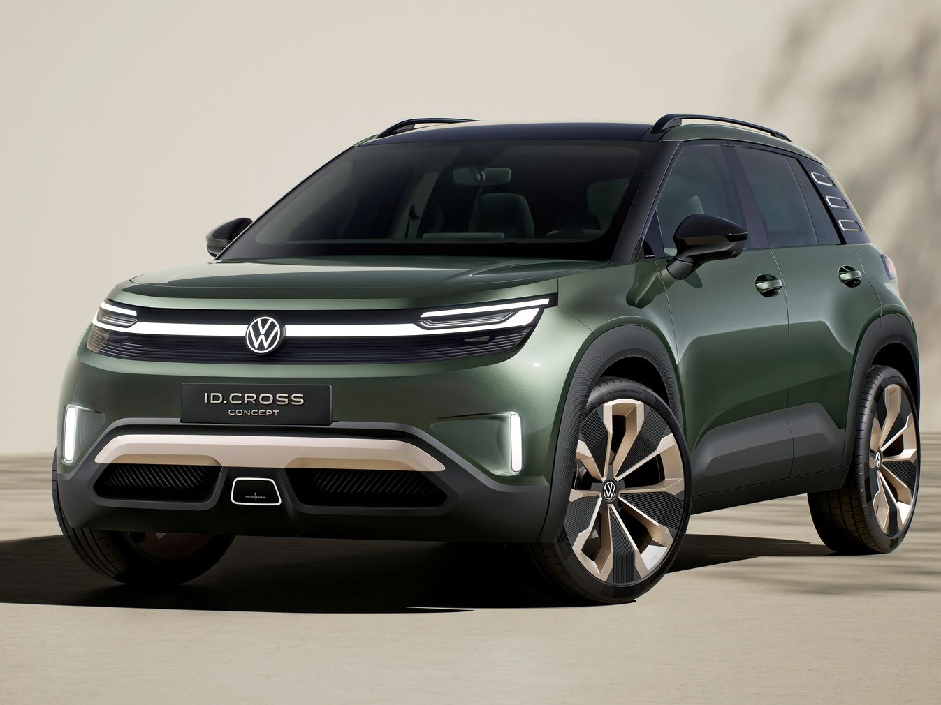 Volkswagen ID. Cross stojí na svetlom povrchu pred krémovou stenou a v pozadí vidieť tieň stromu. Model je štúdiou koncernu.