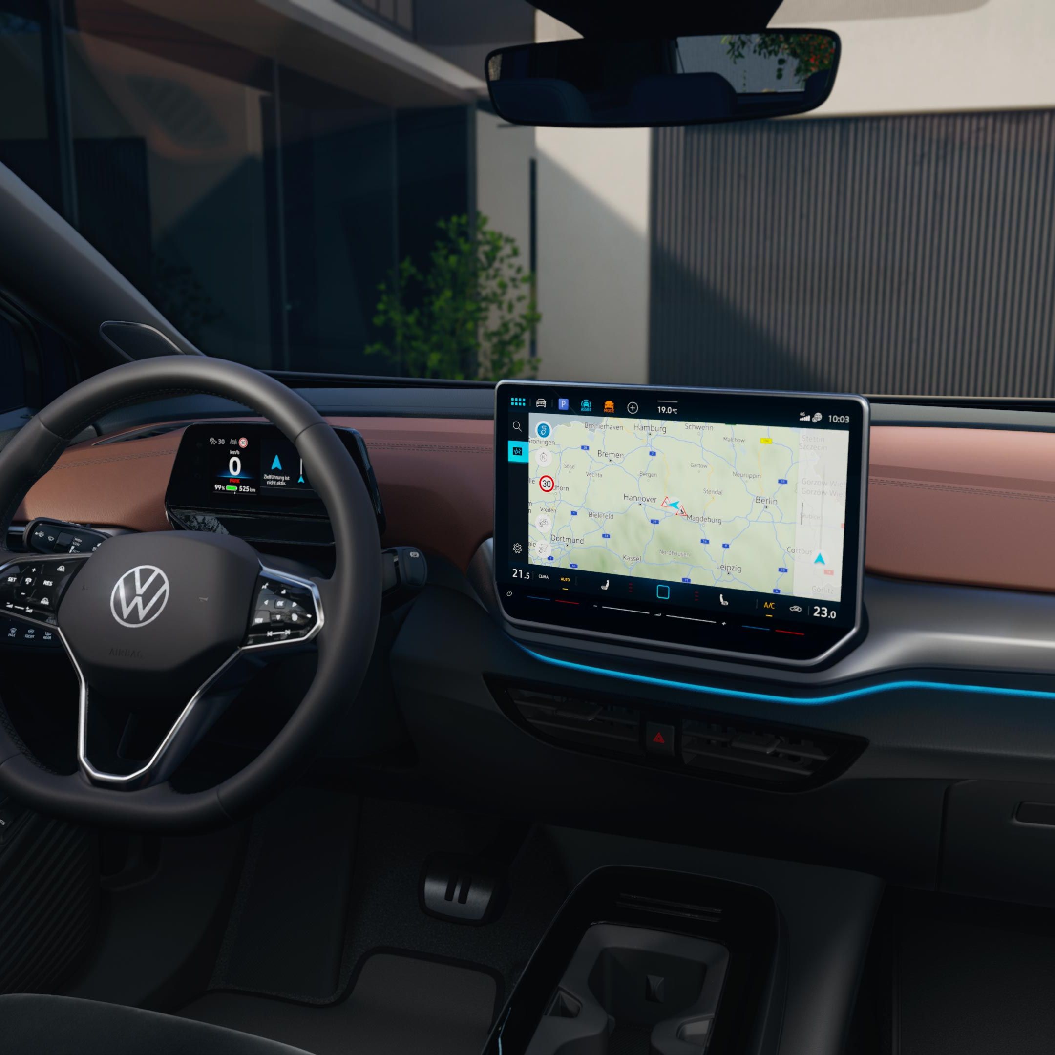 Detail displeja systému infotainment vo VW ID.4. Na displeji je zobrazená navigačná mapa. Palubná doska je potiahnutá hnedou kožou. Cez čelné sklo je vidieť moderná vila.