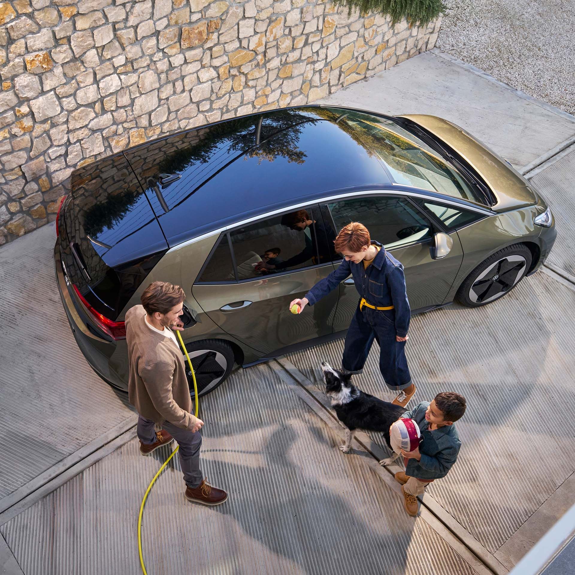 Rodina so psom vedľa vozidla VW ID.3, ktoré sa nabíja nabíjacím káblom