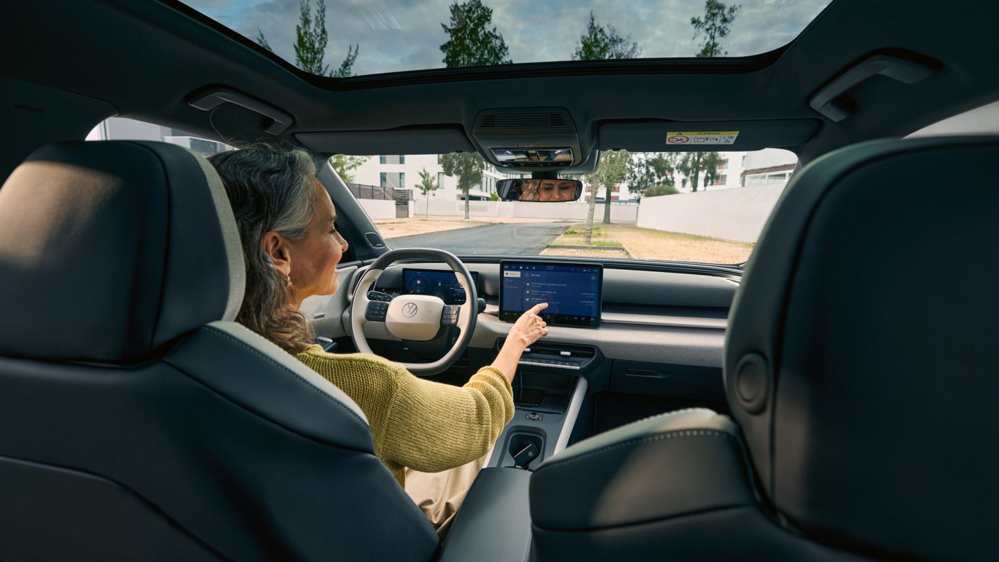 Žena sedí za volantom VW ID. Cross a ovláda infotainment systém.