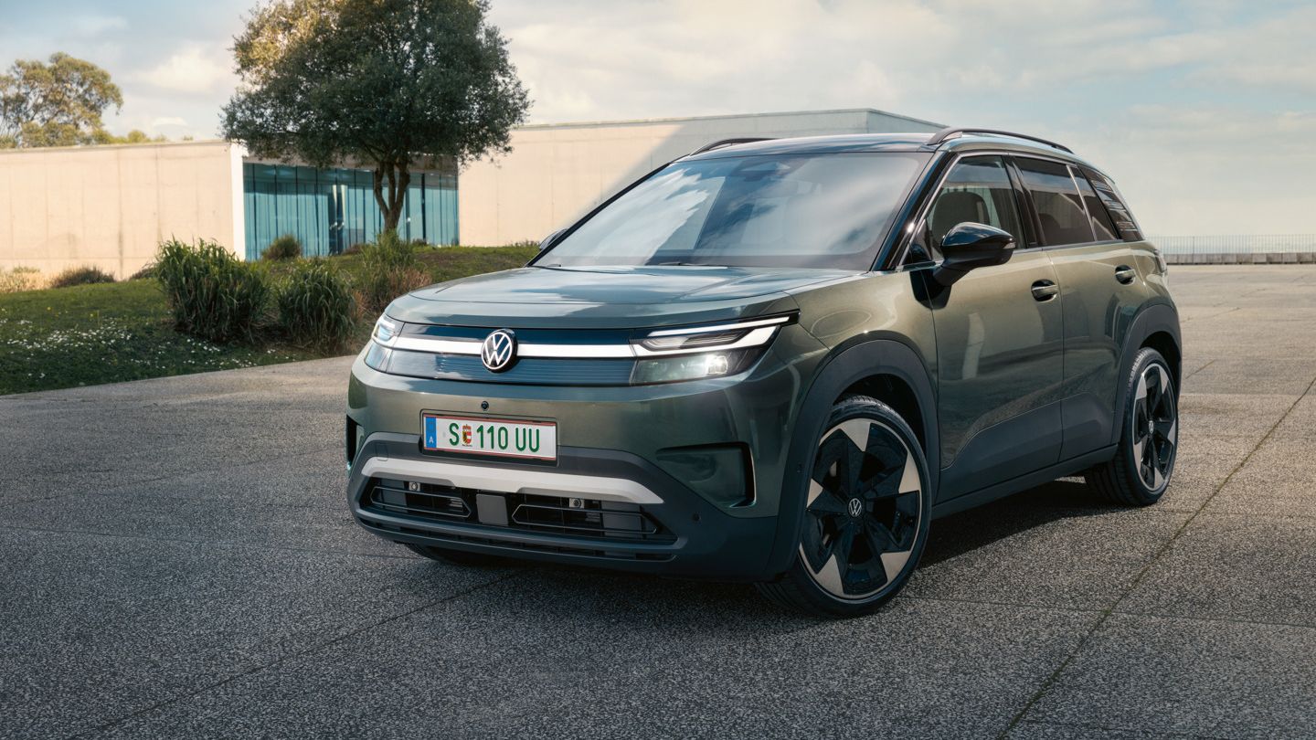 Zelený VW ID. Cross stojí pred modernou sklenenou budovou na betónovom povrchu.