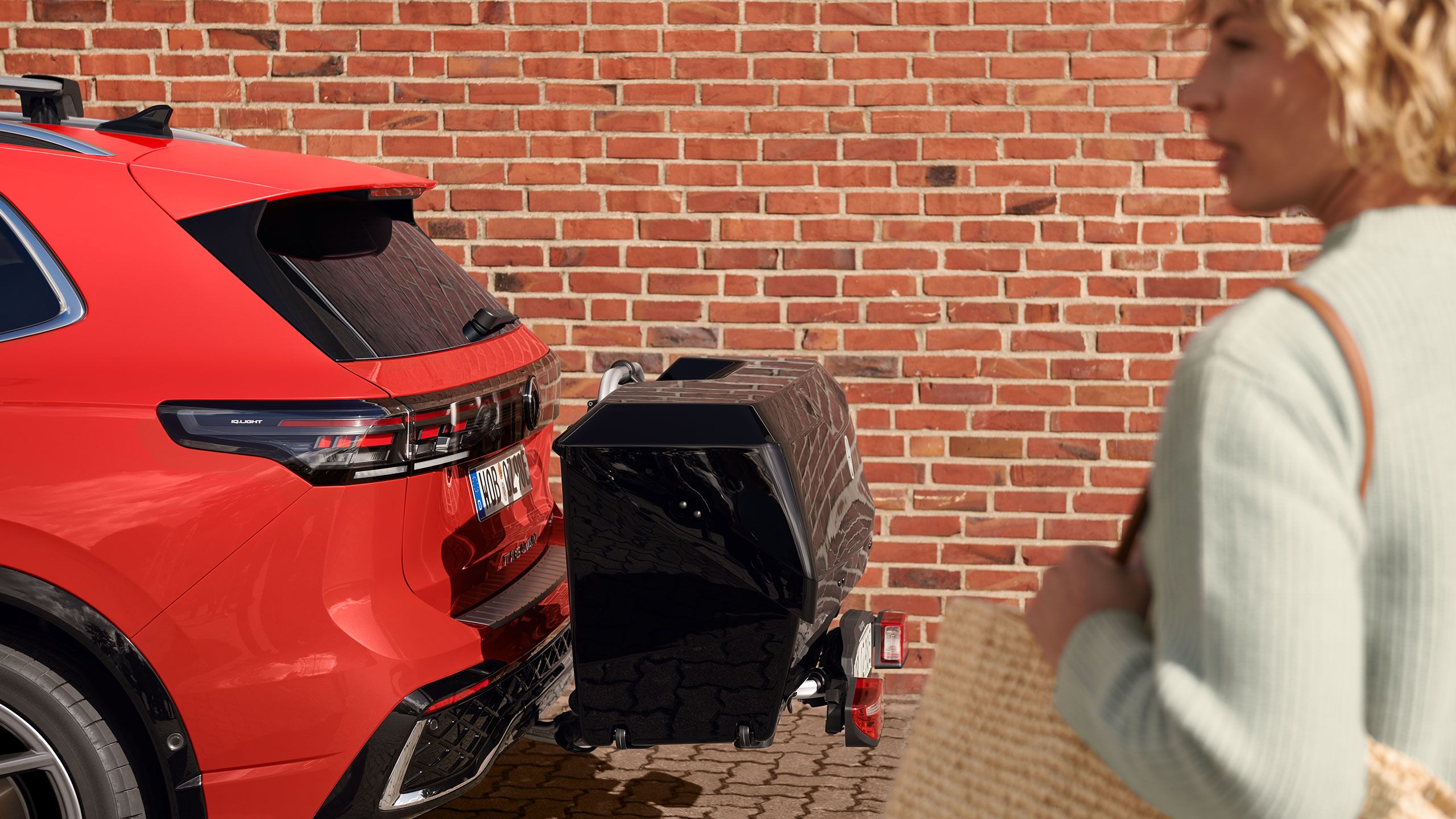 Žena s kabelkou vedľa VW Tiguan so zadným boxom z príslušenstva Volkswagen. 