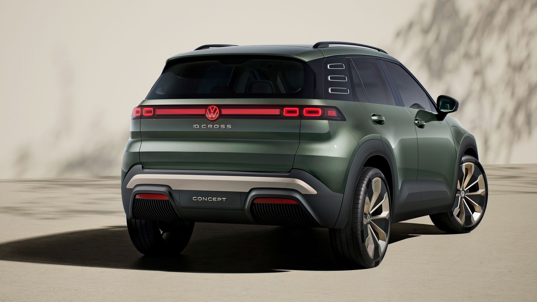 Štúdia Volkswagen ID. Cross zo zadného pohľadu stojí svetlom povrchu pred krémovou stenou. V pozadí vidieť tieň stromu.