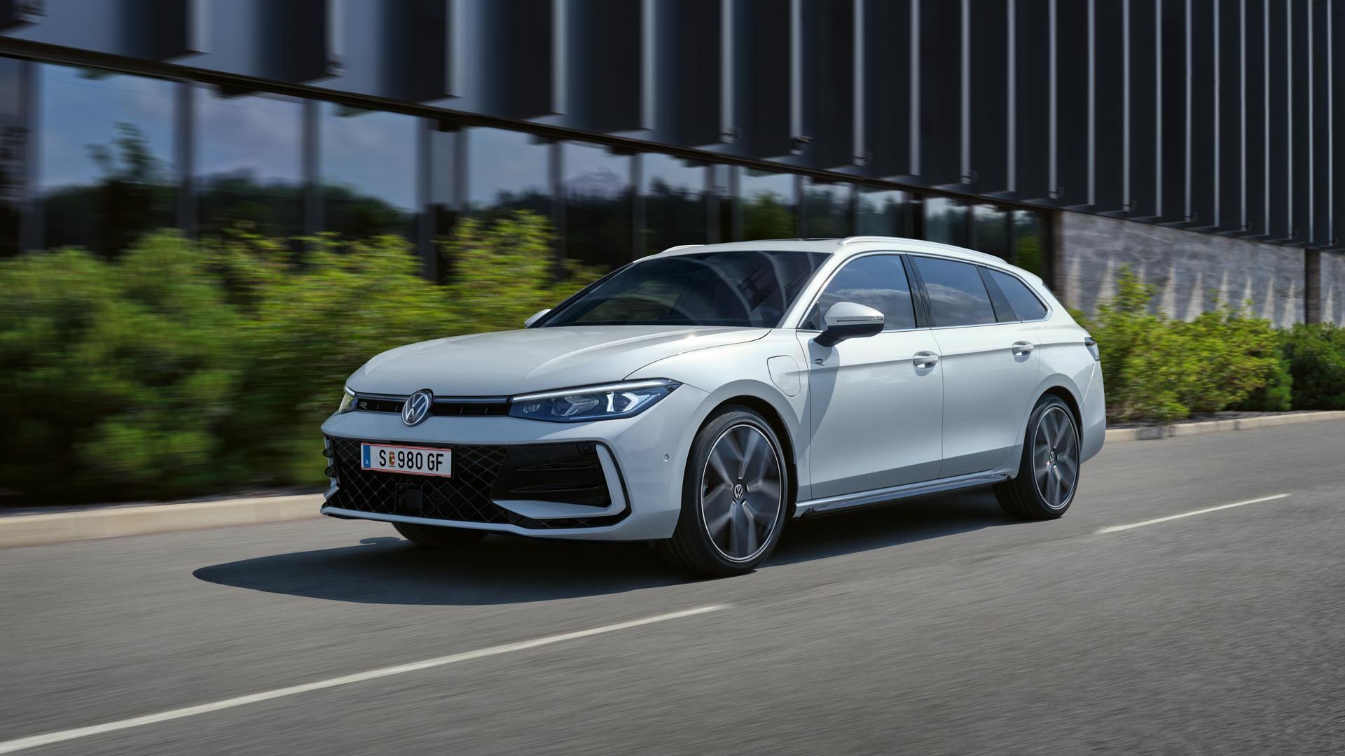 Okolo budovy prechádza biely VW Passat b9 s riadenými tlmičmi a dynamickým riadením.