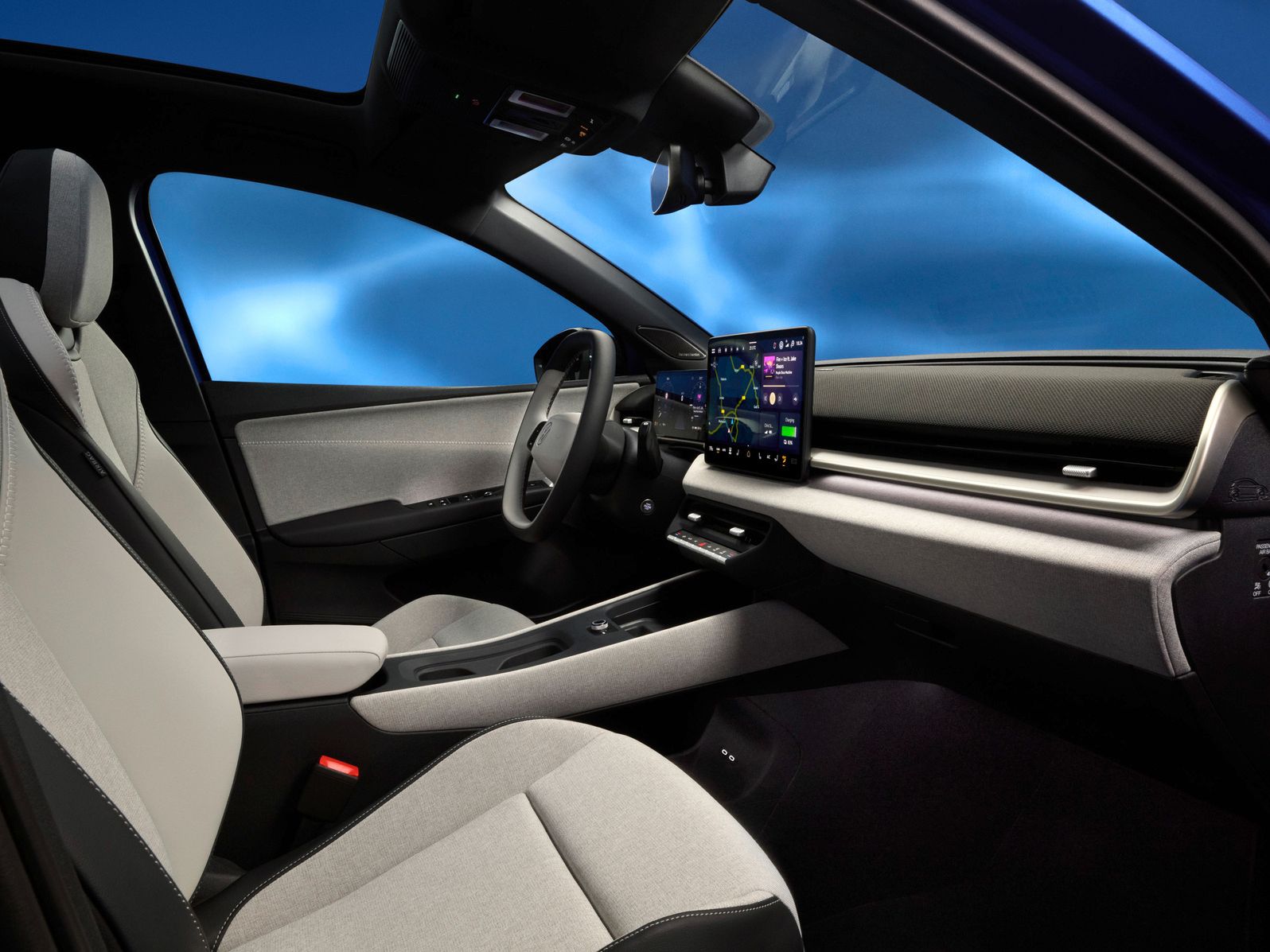 Interiér moderného auta s dvomi prednými sedadlami, dotykovými obrazovkami na palubnej doske a elegantným dizajnom. Na obrazovke sú zobrazené navigačné údaje. Pozadie je modré a vytvára dynamický efekt.