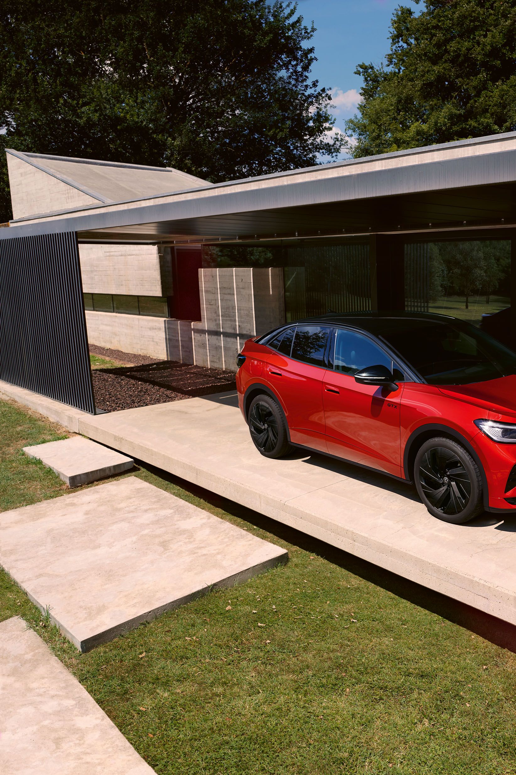 Červené VW ID.5 GTX parkuje pred domom. Muž prechádza okolo neho.