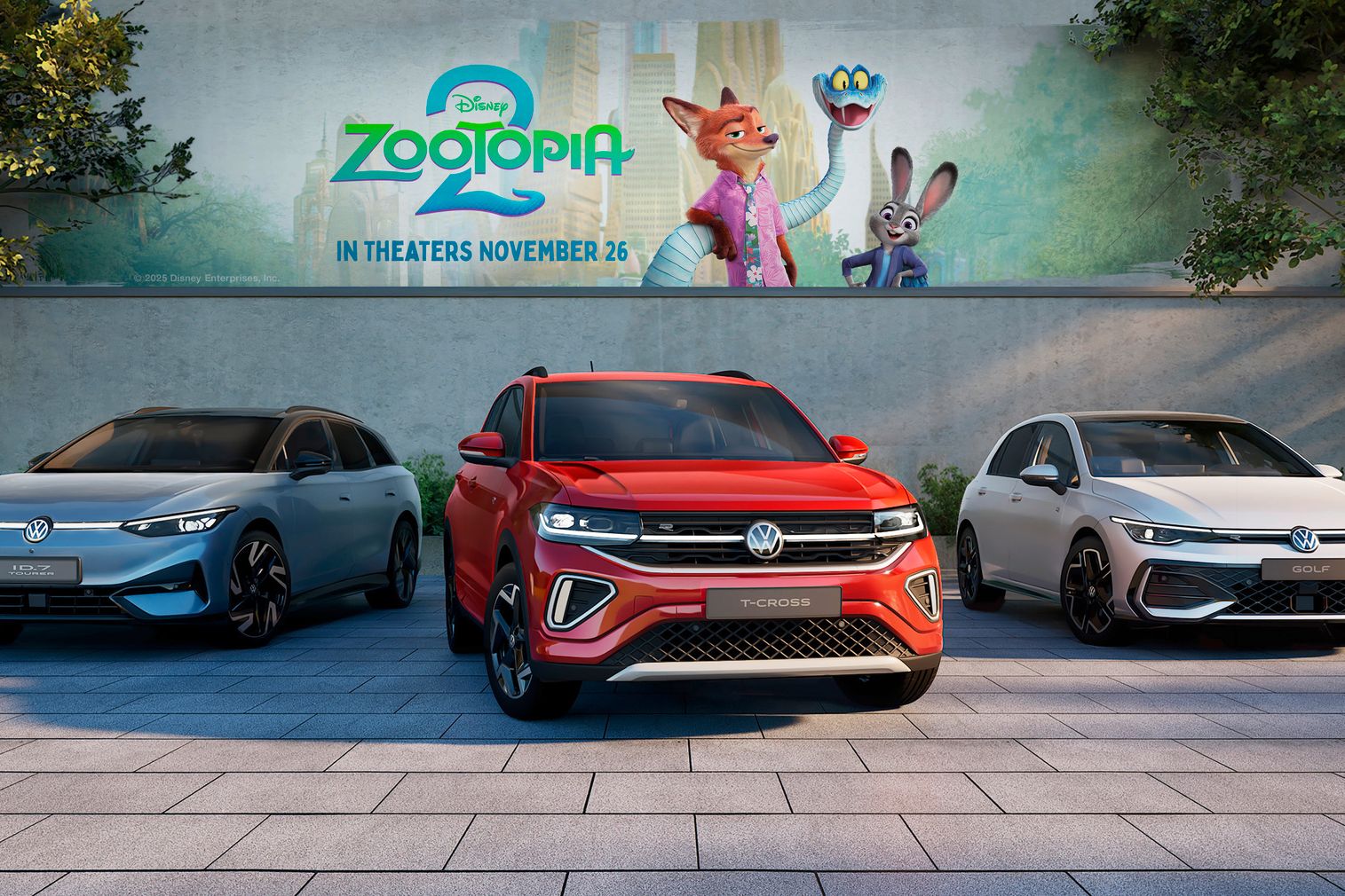 Tri modely automobilov Volkswagen (ID.4X, T-Cross a Golf) zaparkované pred billboardom s filmom Zootopia 2. V pozadí sú stromy a zeleň. Automobily sú rôznych farieb: modrá, červená a biela.