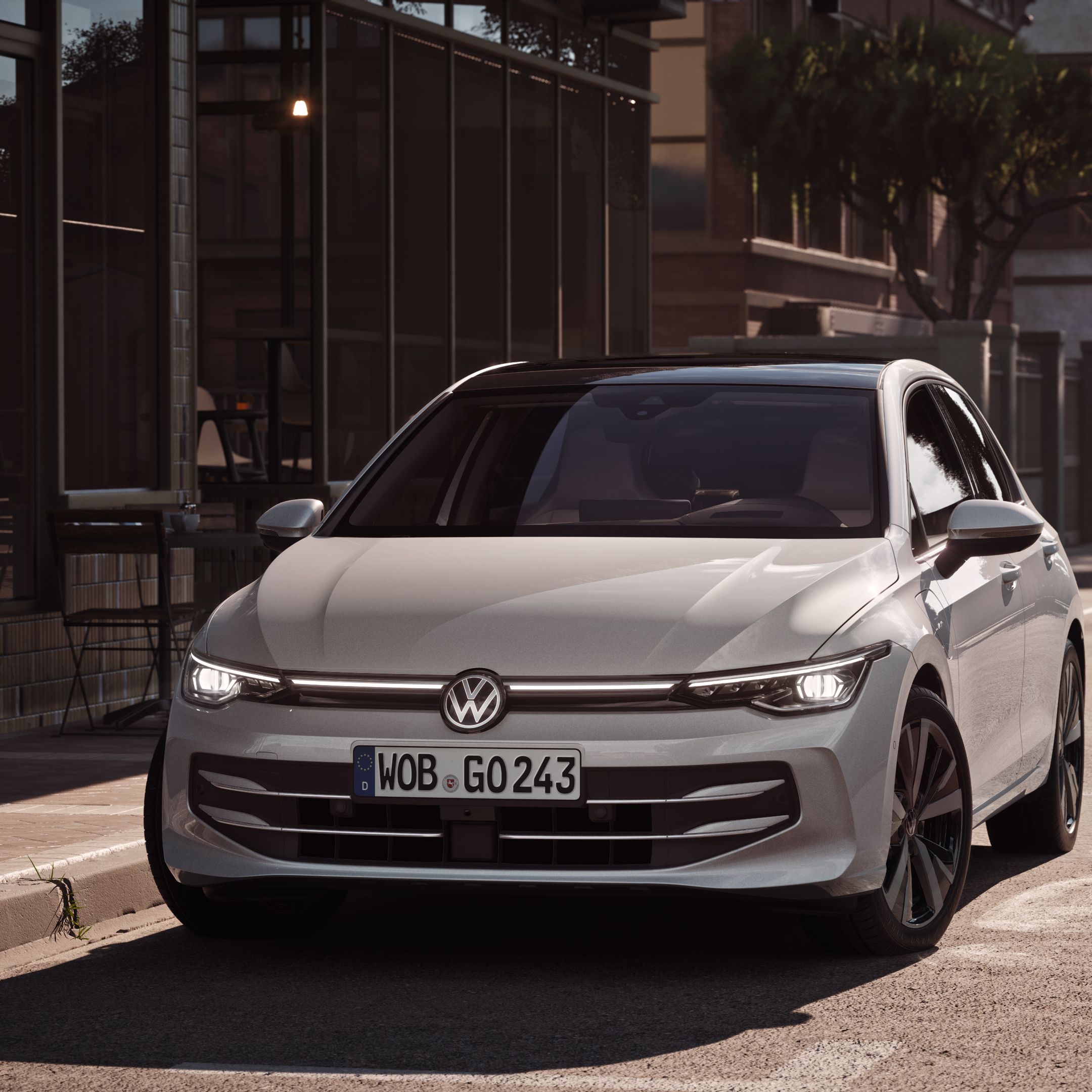 Na ceste pri chodníku pred reštauráciou v meste parkuje biely VW Golf. 