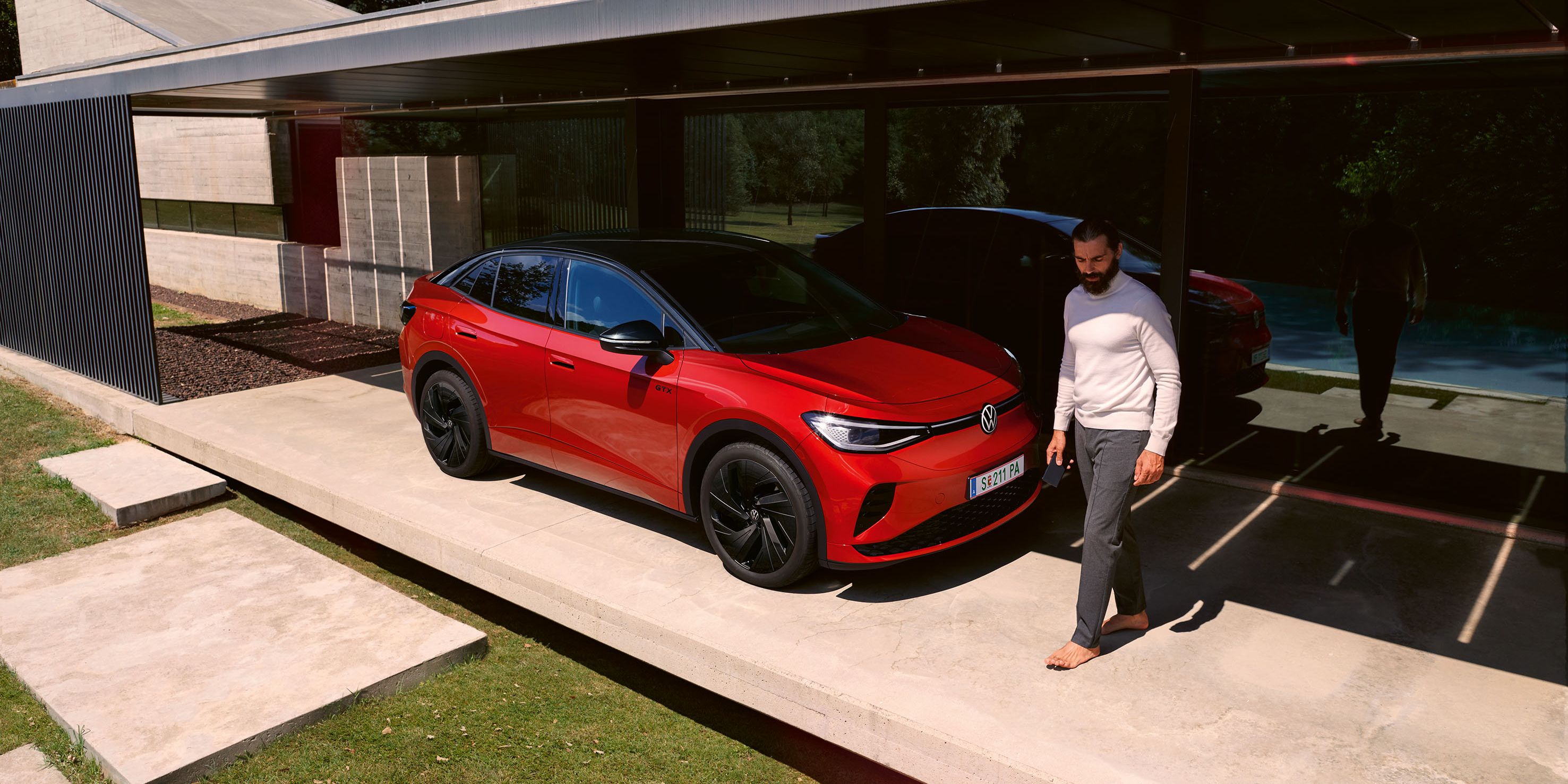Červené VW ID.5 GTX parkuje pred domom. Muž prechádza okolo neho.