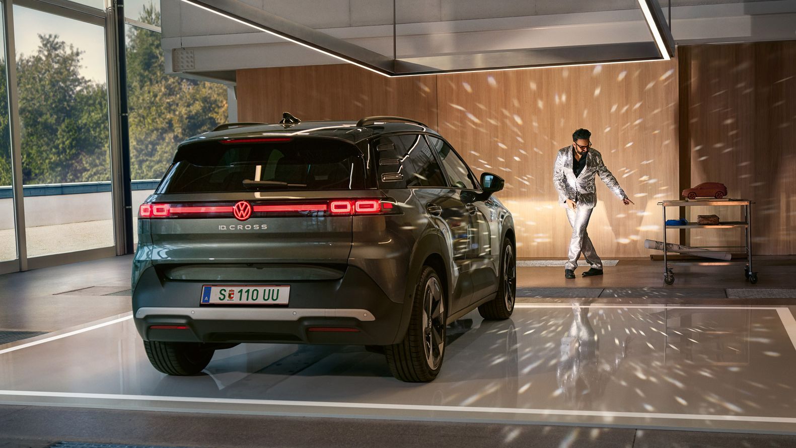 VW ID. Cross stojí v showroome so zapnutými svetlami a osvetľuje tancujúcího muža v trblietavom obleku.