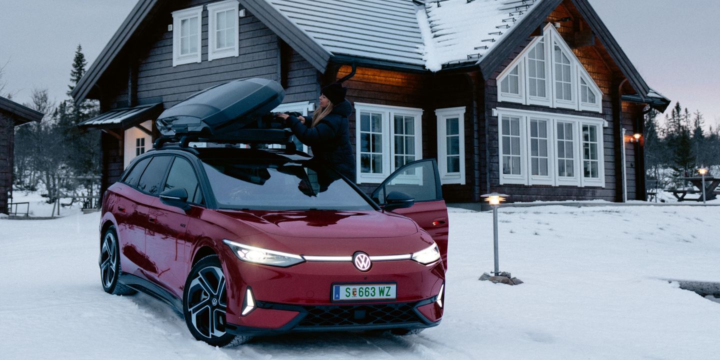 Červený ID.7 Tourer GTX so strešným boxom stojí v snehu pred domom.