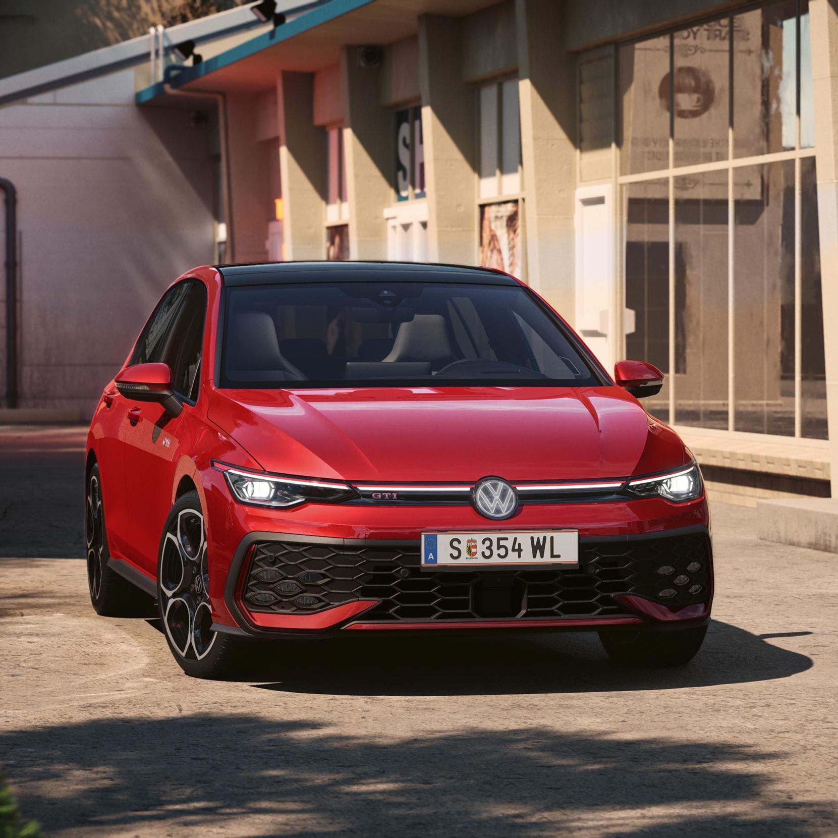 Červený automobil značky Volkswagen so športovým dizajnom zaparkovaný pred svetlou budovou. Vozidlo má zasvietené predné svetlomety.  