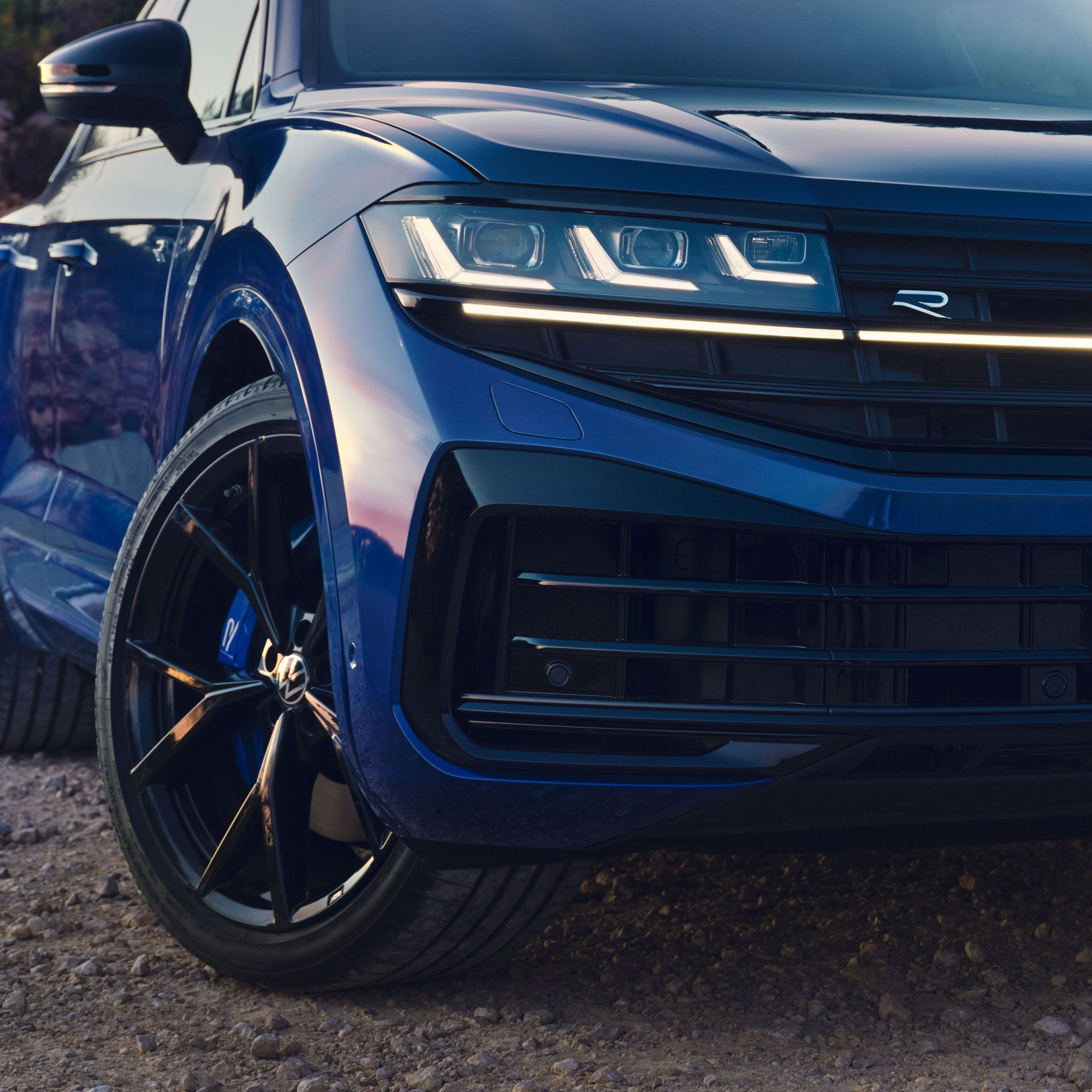 Detailný pohľad predné partie VW Touareg R eHybrid zameraný na dizajnový disk kolesa a Matrix LED svetlomet. Na mriežke chladiča je logo R.