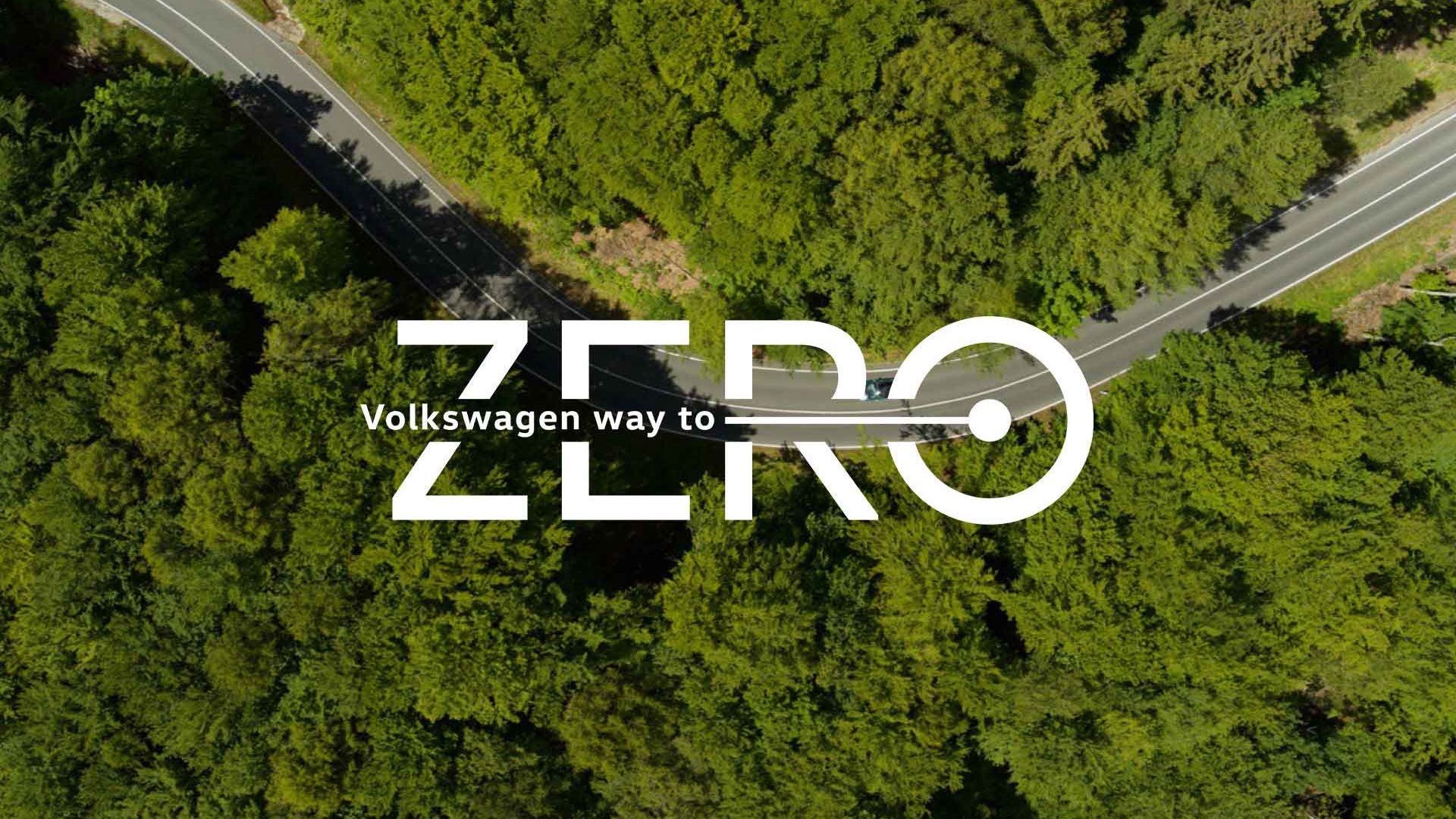 VW Way to Zero uprostred fotografie z vtáčej perspektívy na cestu, ktorá sa kľukatí medzi stromami.