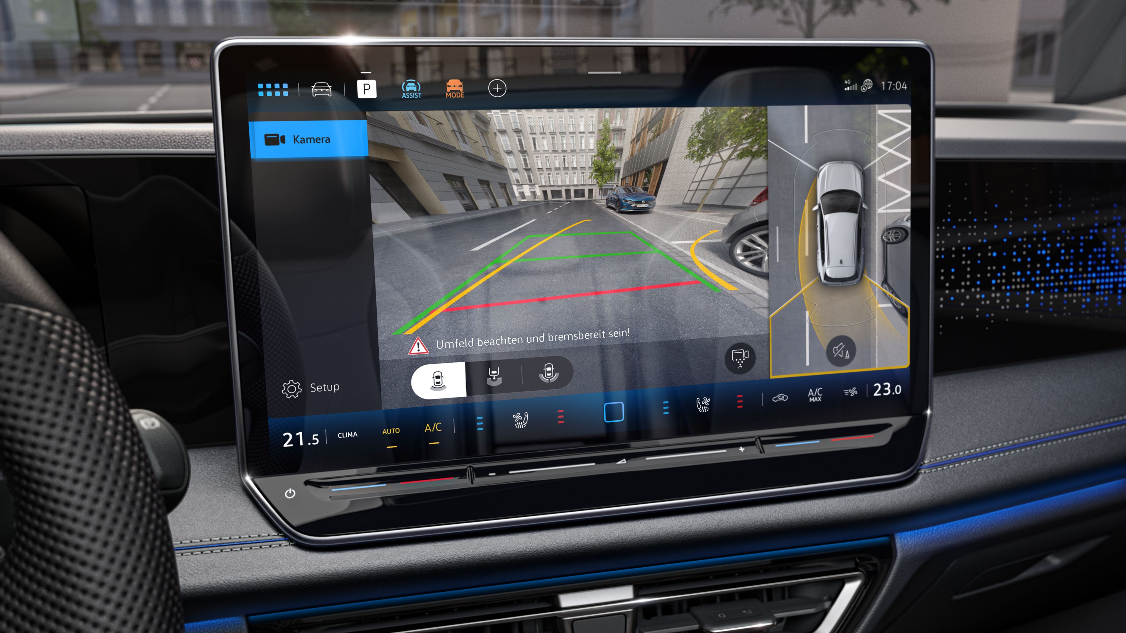 Displej systému infotainment ukazuje obraz z cúvacej kamery, ktorá zobrazuje priestor za vozidlom. Vidieť tiež farebne pomocné línie pre bezpečný pohyb a parkovanie. Vpravo je zobrazené auto pripravené parkovať.