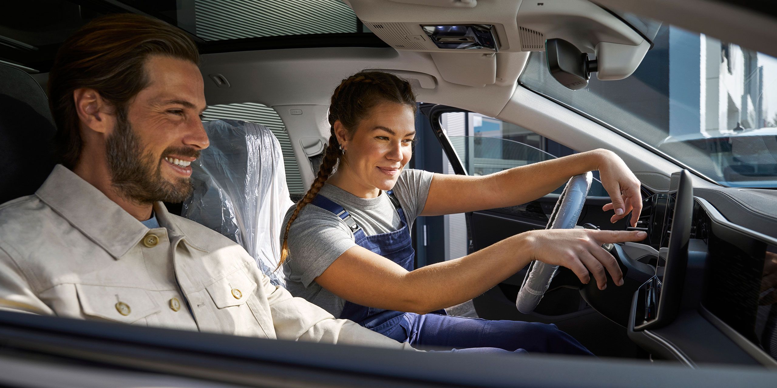 Zamestnanec servisu VW a muž sediaci v aute VW, ktorý sa pozerá na infotainment systém kvôli aktualizáciám softvéru.