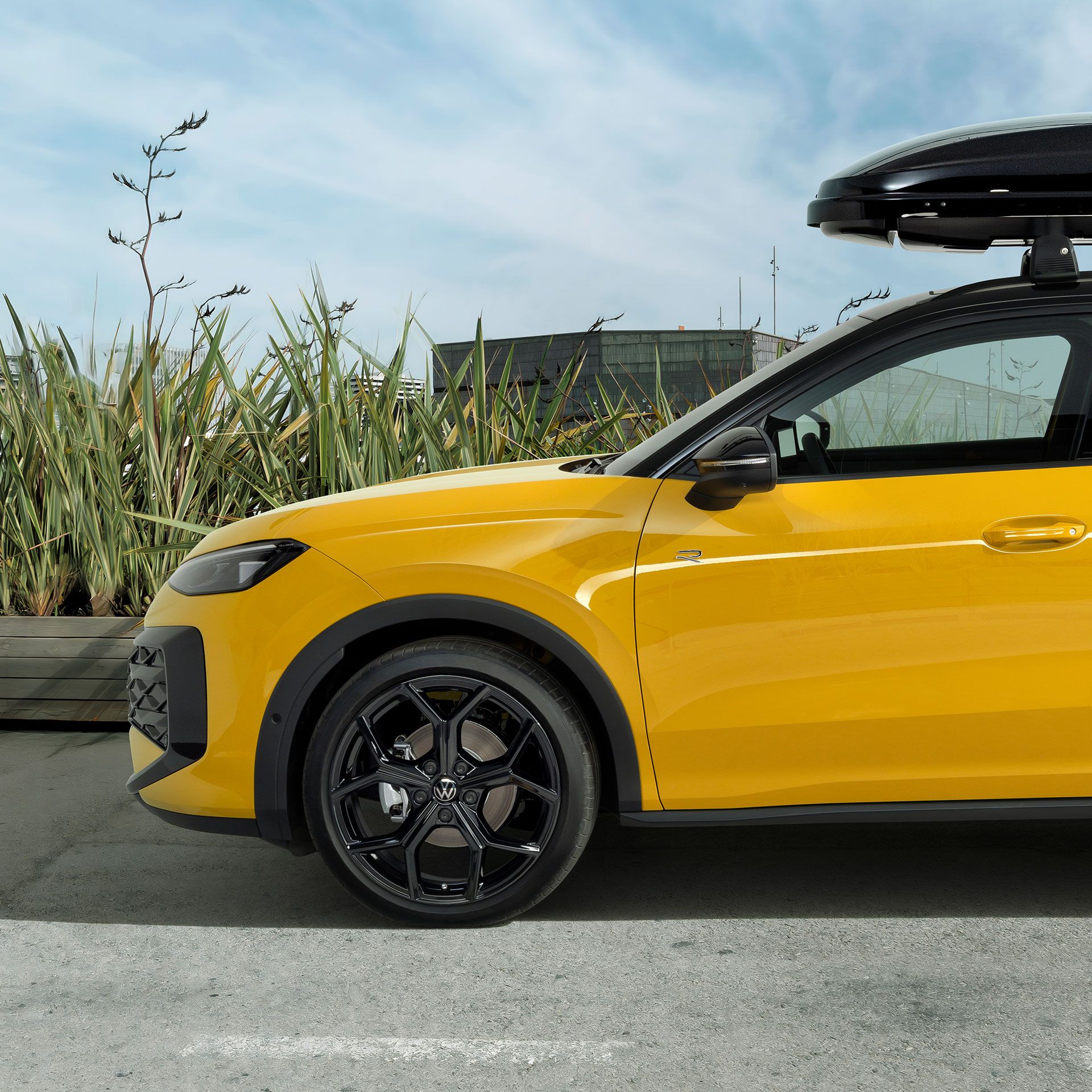 Žltý VW T-Roc so strešným boxom zaparkovaný na ceste – príslušenstvo T-Roc