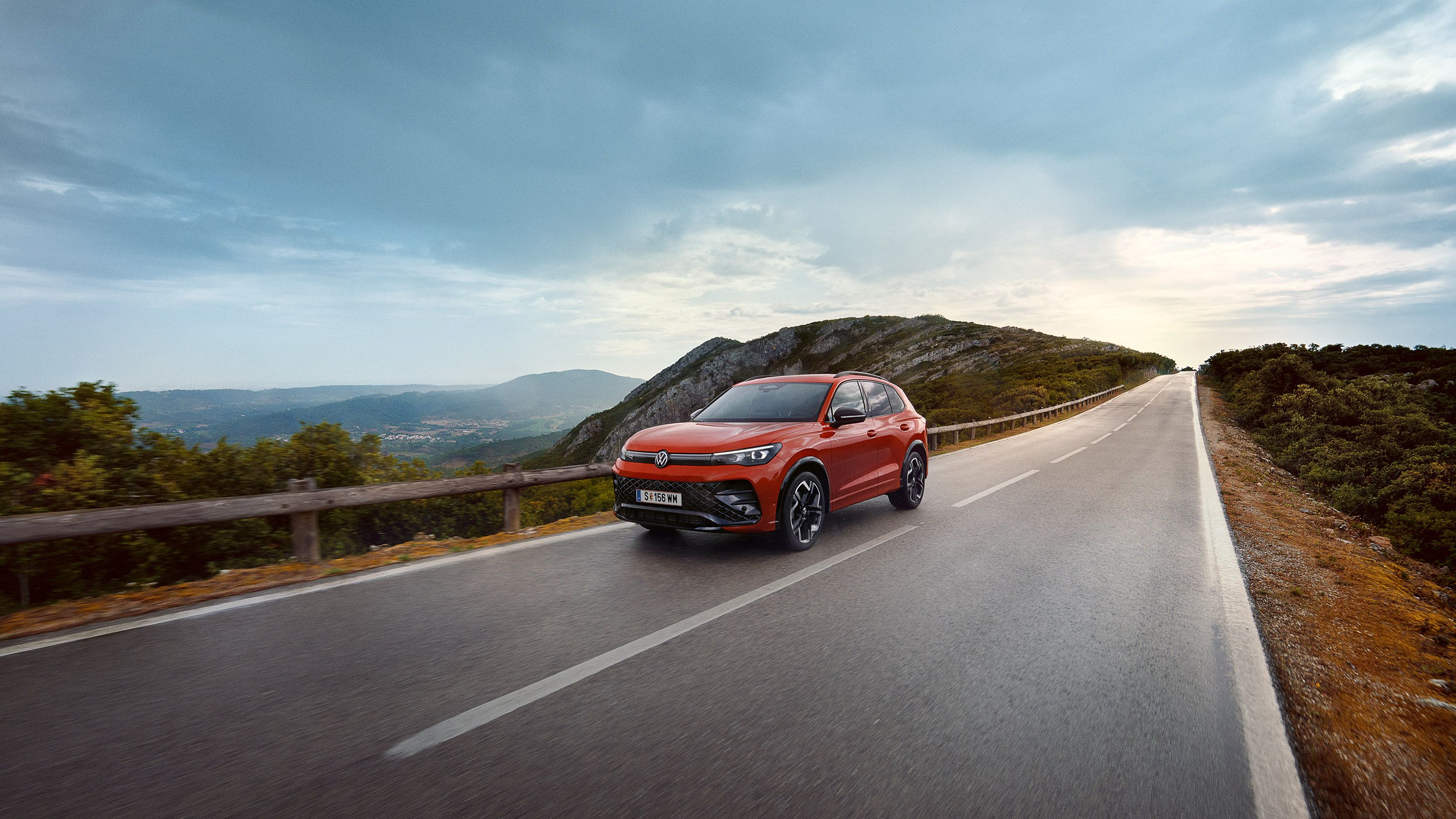 Červený VW Tiguan jazdí po ceste.