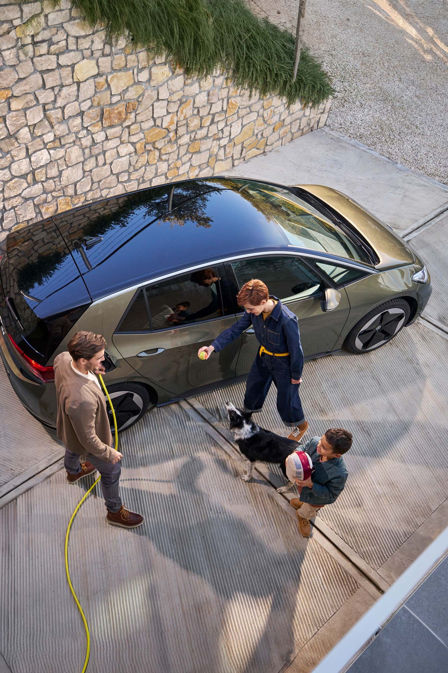 Rodina so psom vedľa vozidla VW ID.3, ktoré sa nabíja nabíjacím káblom