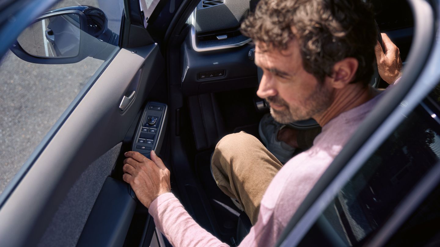 Muž vo vozidle VW ID.3 Neo. Dvere vodiča so štyrmi okennými ovládačmi sú napoly otvorené.