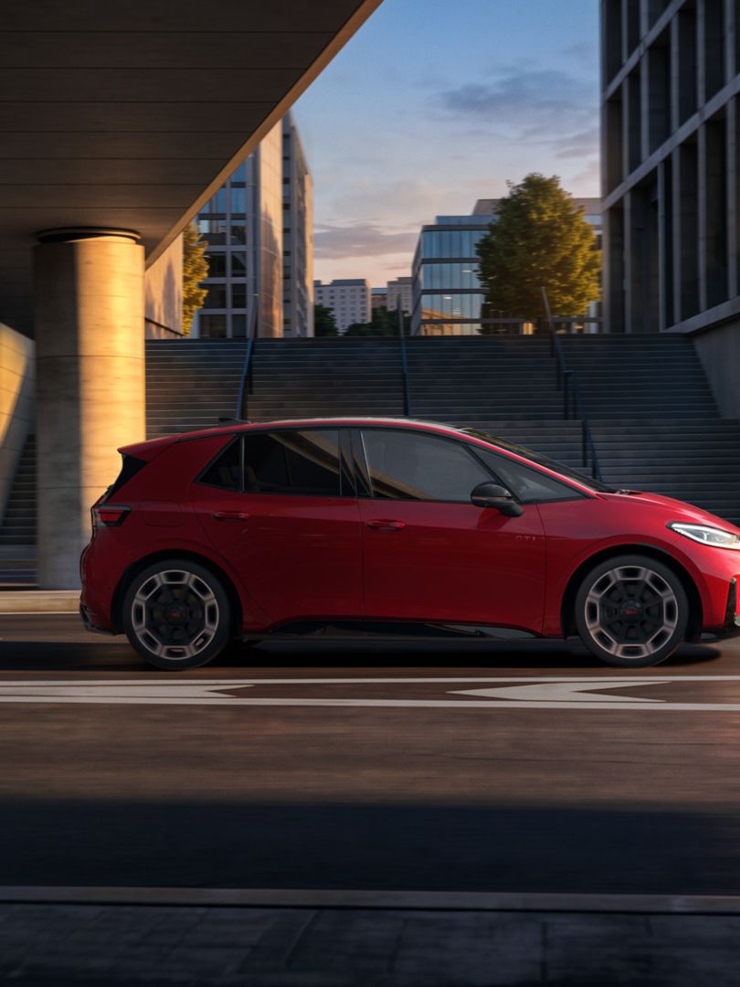 [AI-modified] – Červené VW ID.3 GTI z bočného pohľadu počas jazdy pod mostom v meste.
