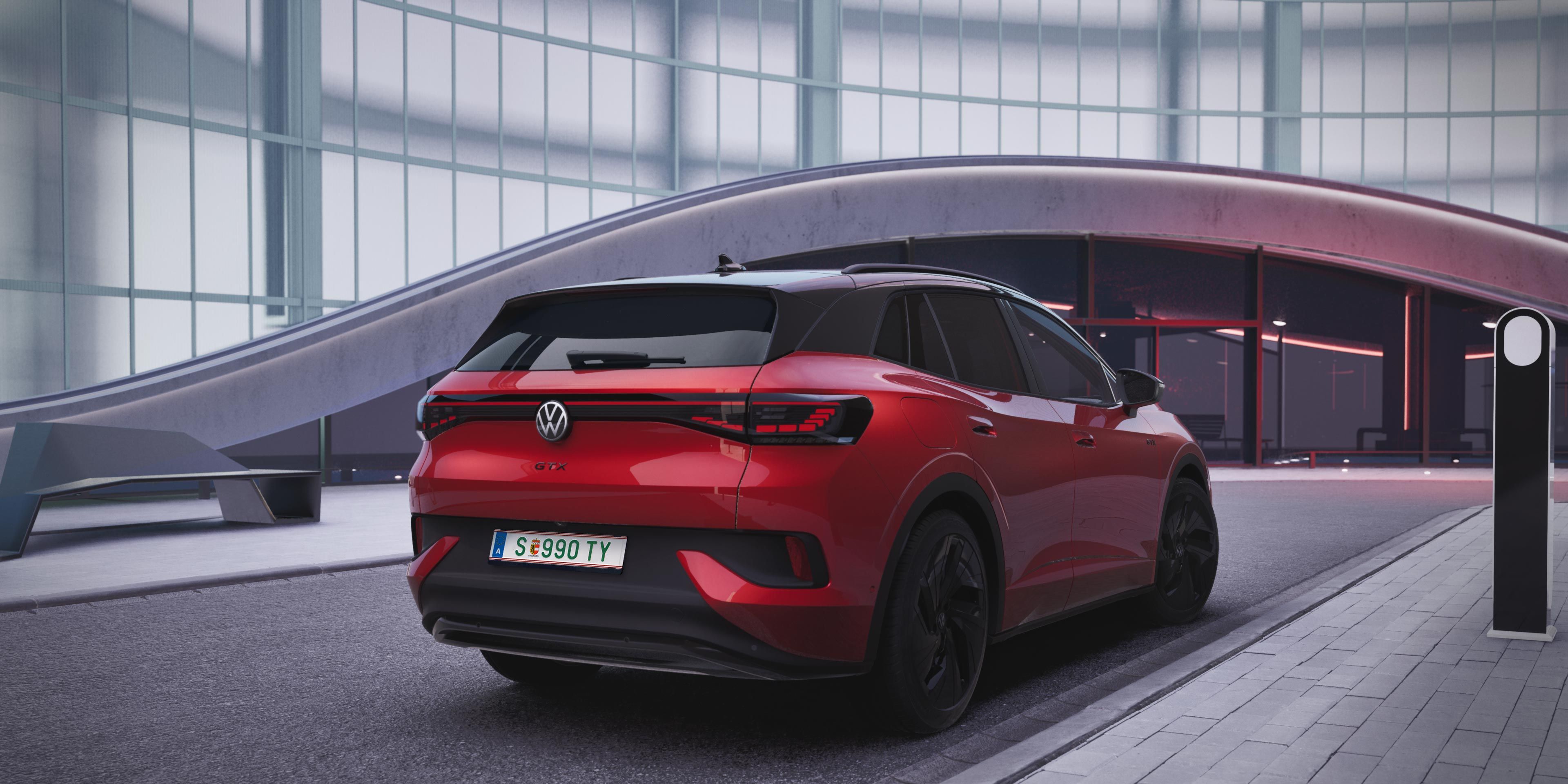 Červené SUV Volkswagen ID.4 GTX zaparkované pred modernou budovou so sklenenou fasádou. Automobil má čiernu sklenenú strechu a čierne disky kolies. V pozadí je futuristická architektúra.
