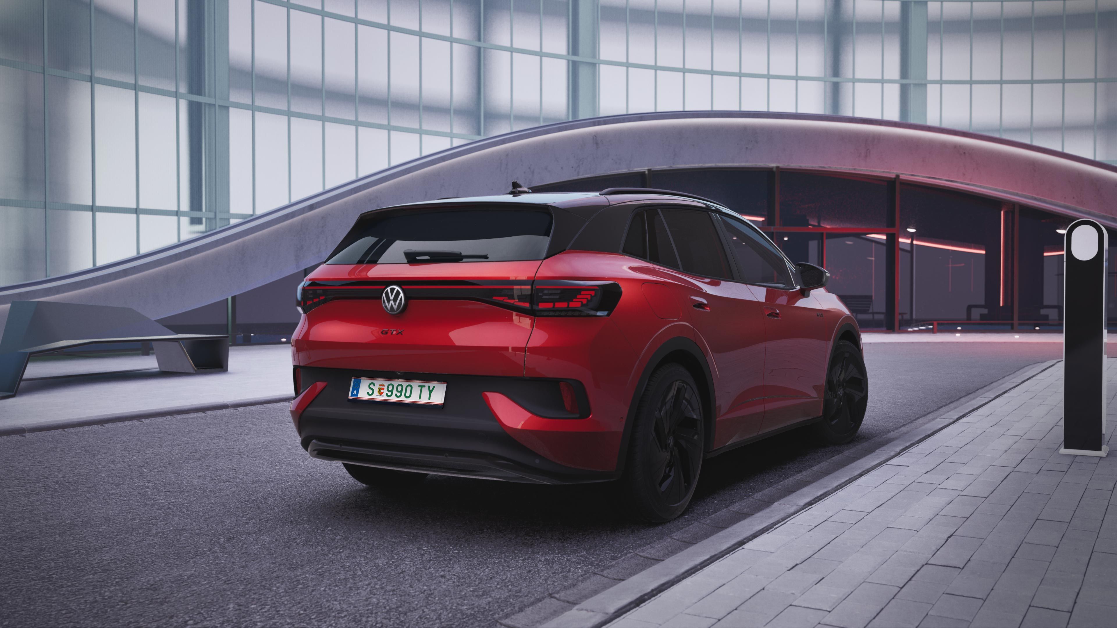 Červené SUV Volkswagen ID.4 GTX zaparkované pred modernou budovou so sklenenou fasádou. Automobil má čiernu sklenenú strechu a čierne disky kolies. V pozadí je futuristická architektúra.