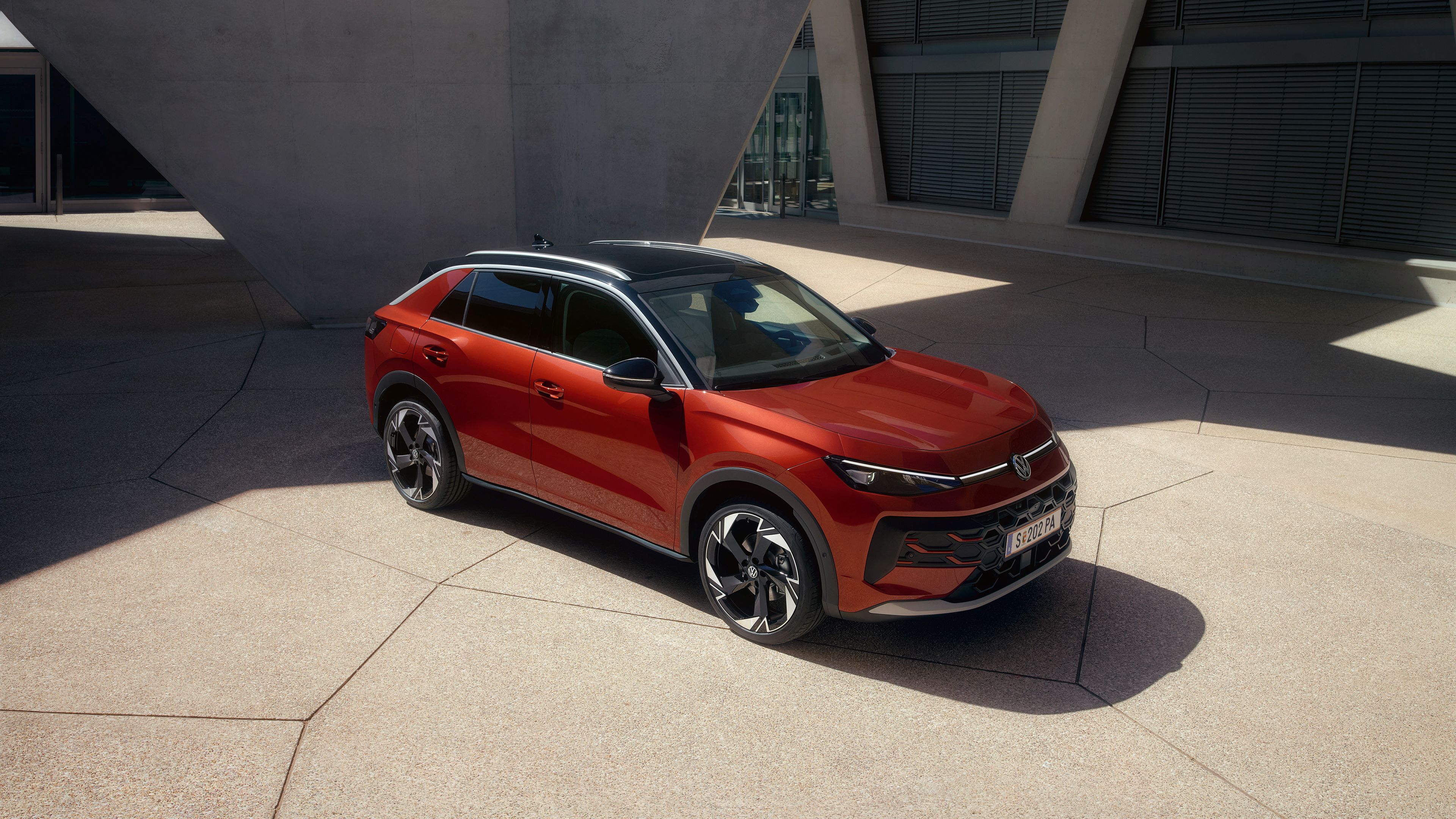 Červený VW T-Roc Style stojí pred modernou budovou počas slnečného dňa.