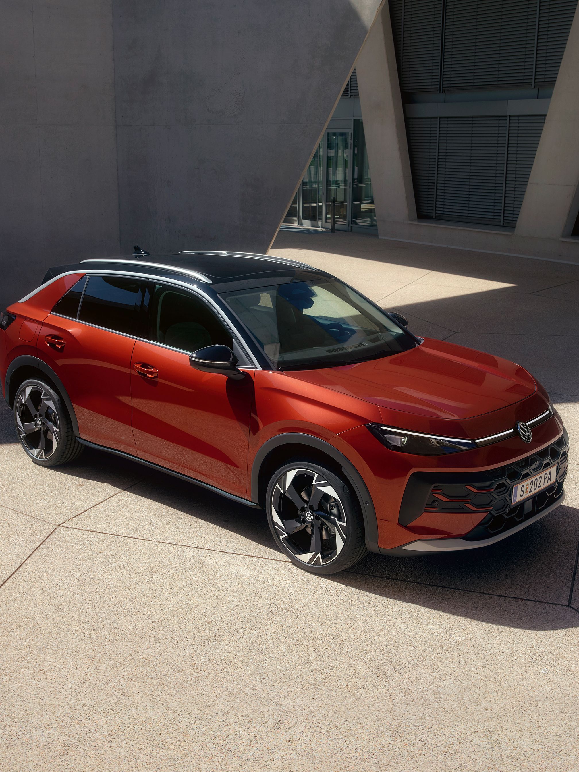 Červený VW T-Roc Style stojí pred modernou budovou počas slnečného dňa.