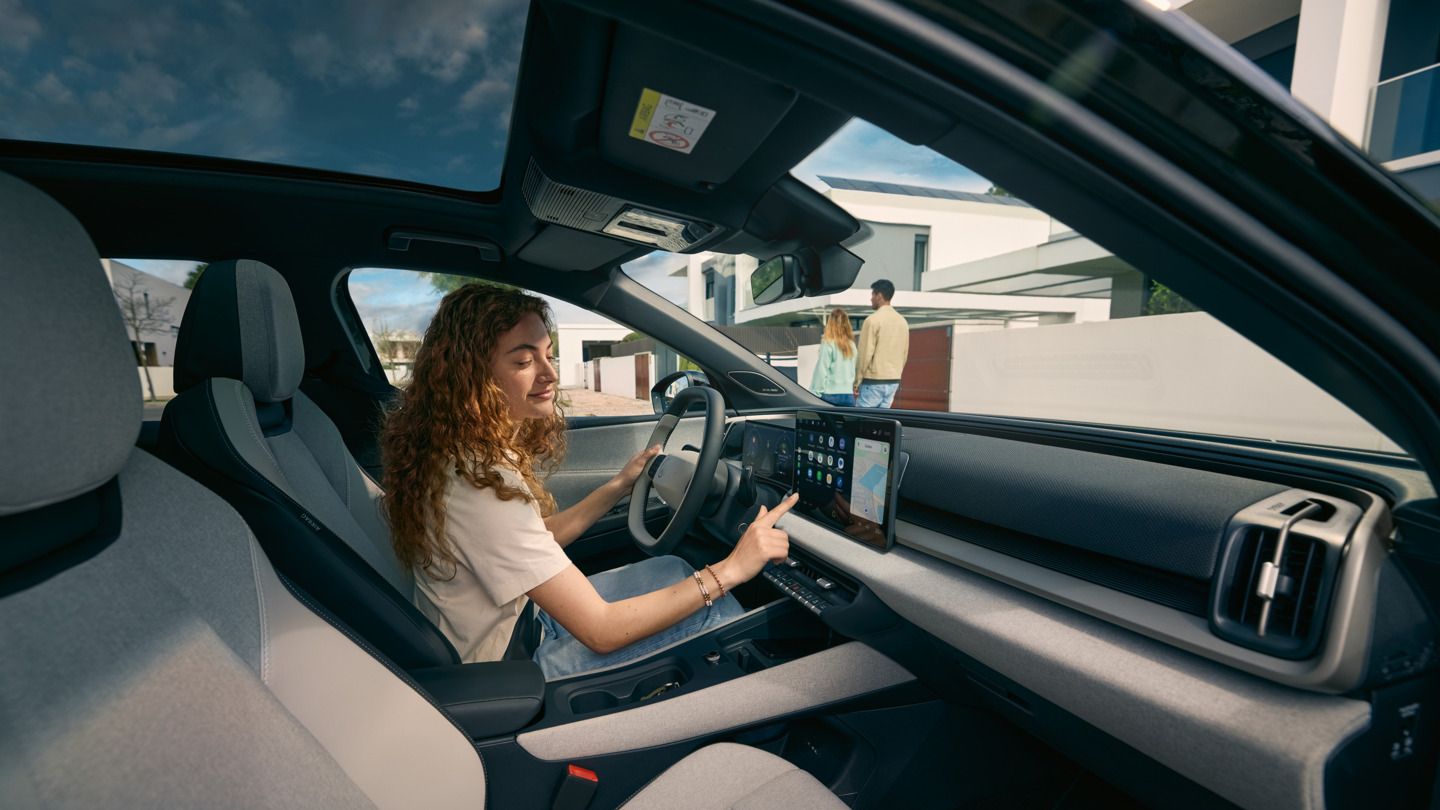 Mladá žena sedí za volantom VW ID Cross a ovláda infotainment systém.