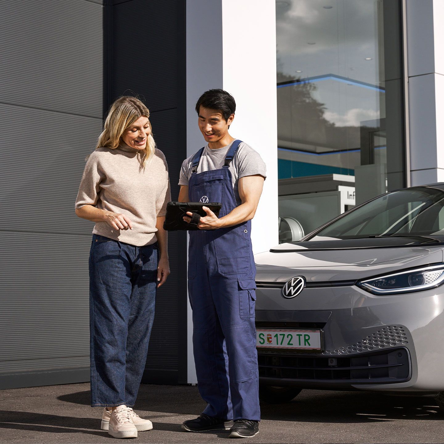 Technik spoločnosti Volkswagen a zákazníčka stoja pred sivým Volkswagenom ID.3.