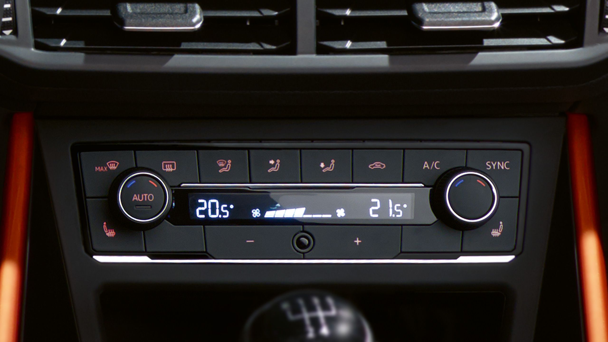 Ovládací panel klimatizácie s digitálnym displejom ukazuje teplotu 20,5°C na jednej strane a 21,5°C na druhej strane. Panel obsahuje tlačidlá na automatický režim, vyhrievanie, chladenie a synchronizáciu teploty. Pod panelom je viditeľná časť radiacej páky.