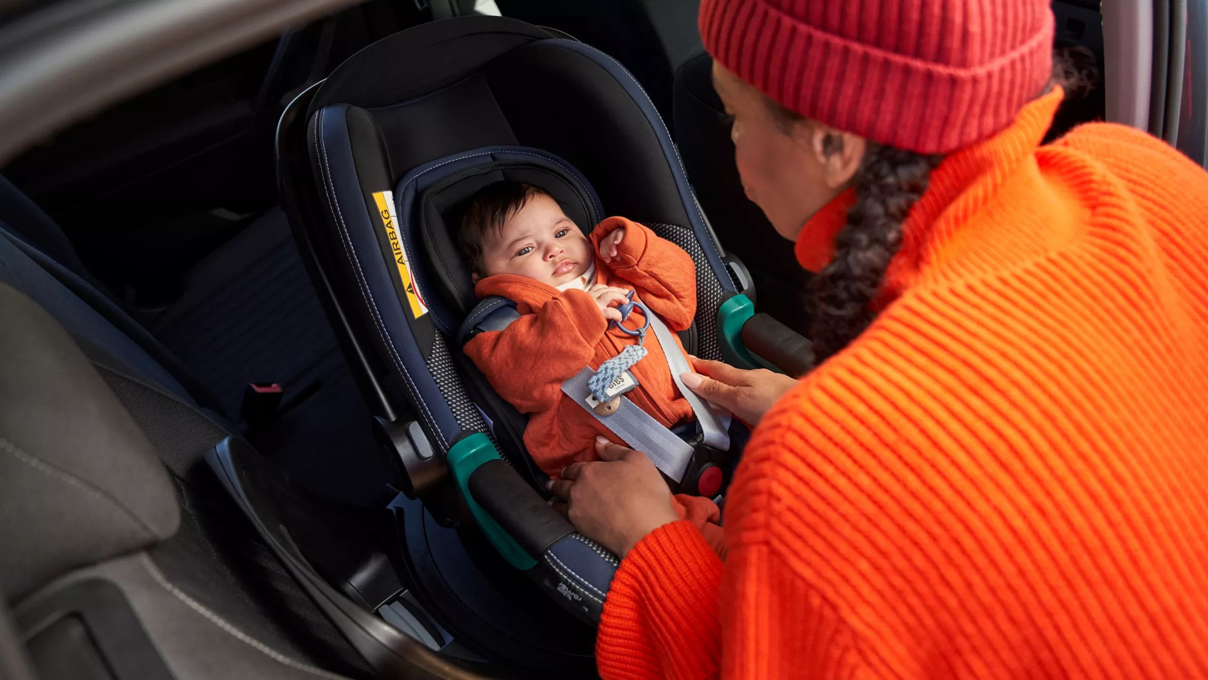 Žena pripína dieťa, ktoré sedí v detskej sedačke VW príslušenstva