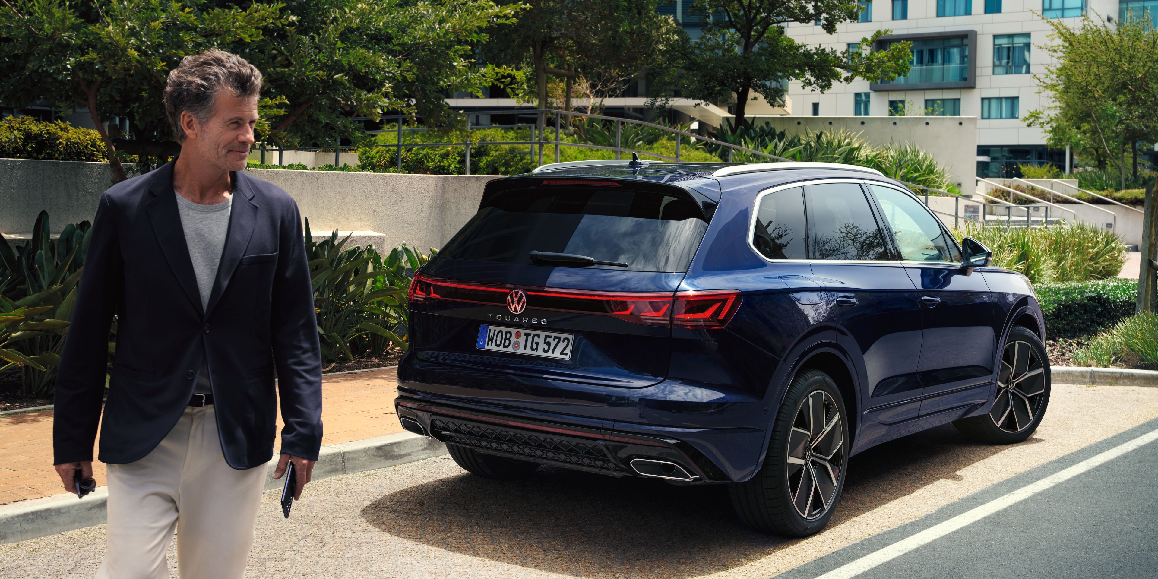Muž kráča od svojho v meste zaparkovaného vozidla Volkswagen Touareg.