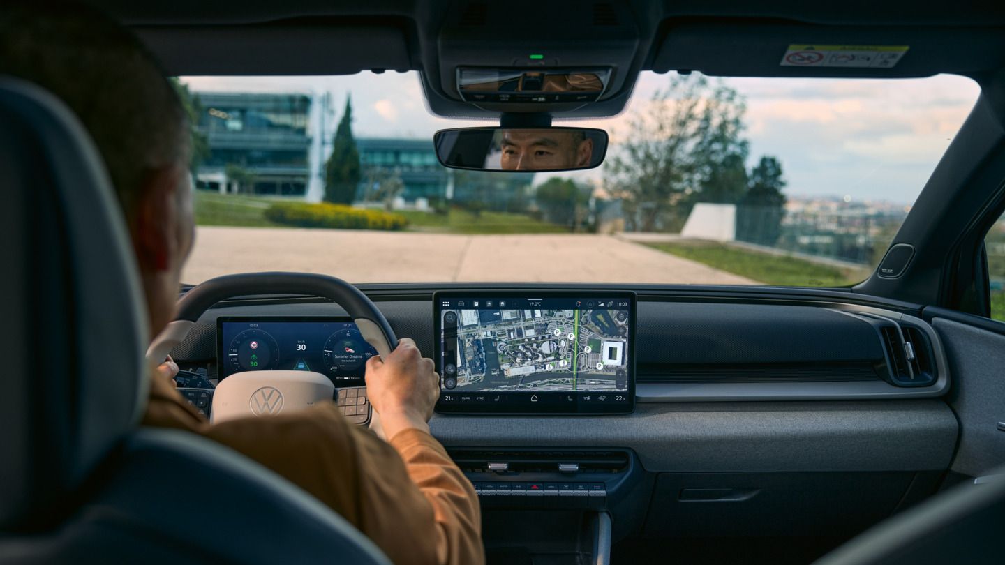 Pohľad zo zadného sedadla do kabíny vodiča na VW ID. Cross s aktívnou navigáciou na obrazovke systému infotainment.