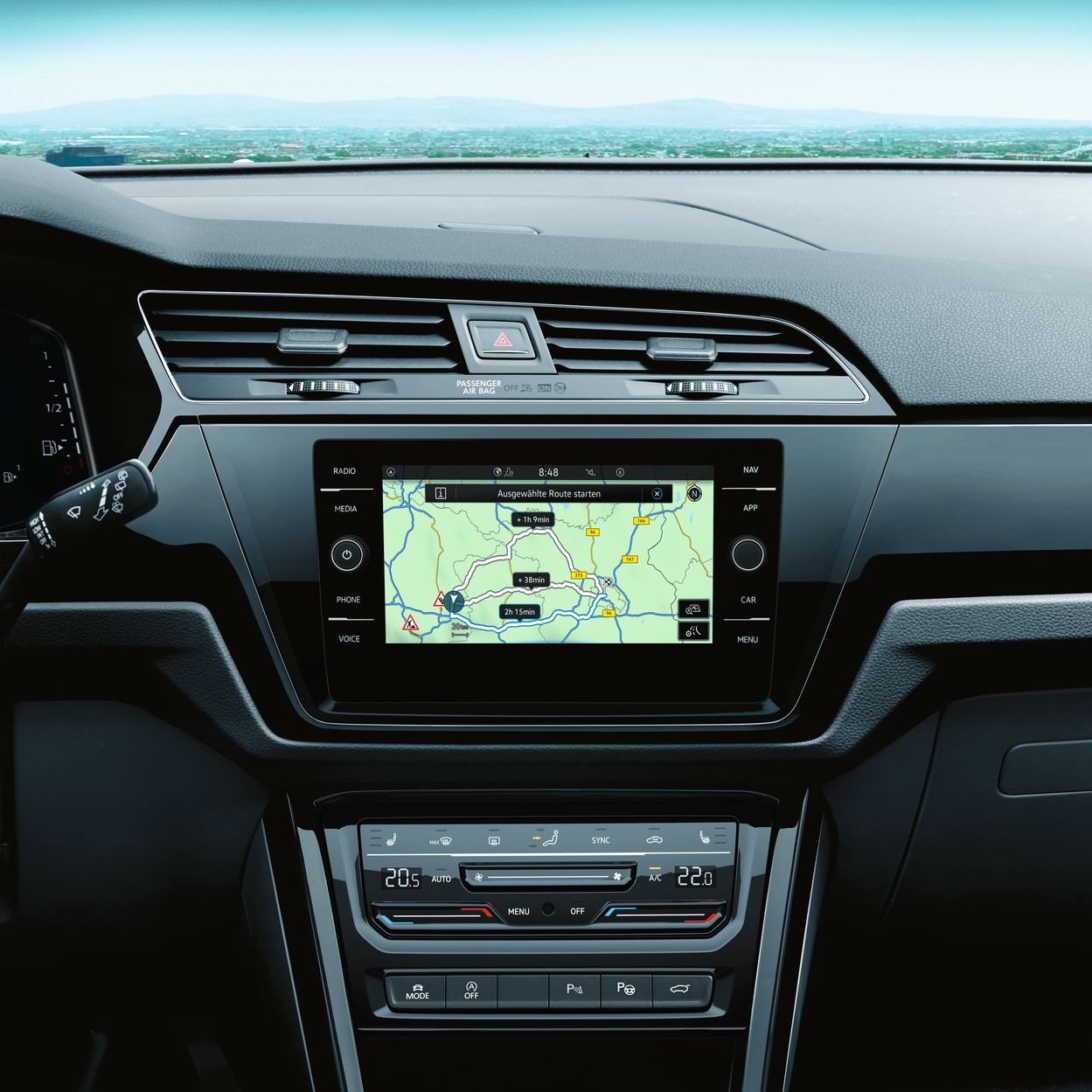 Pohľad na palubnú dosku automobilu s multimediálnym systémom. Na displeji je navigačná mapa. Pod ním je ovládanie klimatizácie.