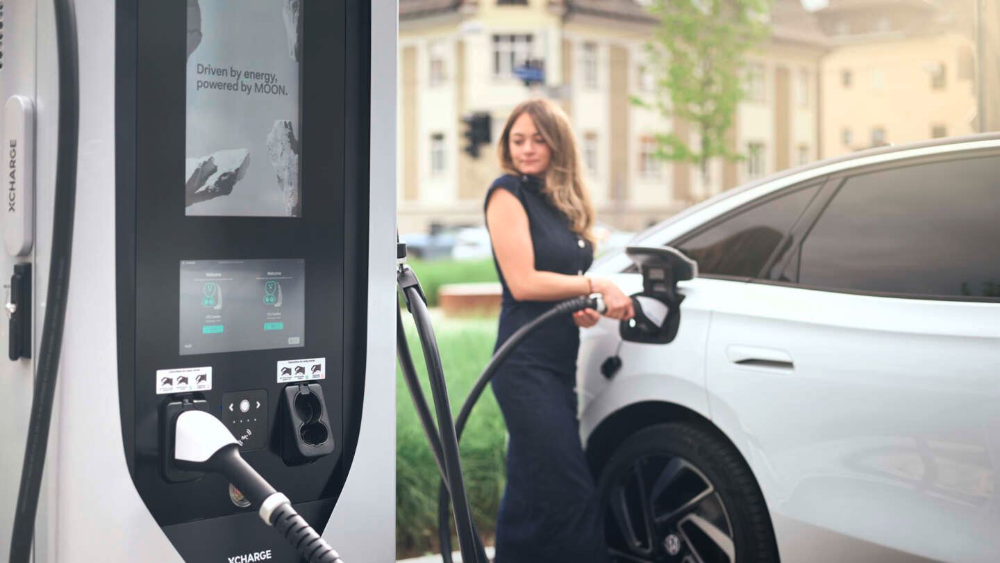 Žena nabíja biely VW ID.7 elektrickou energiou prostredníctvom nabíjacej stanice MOON.