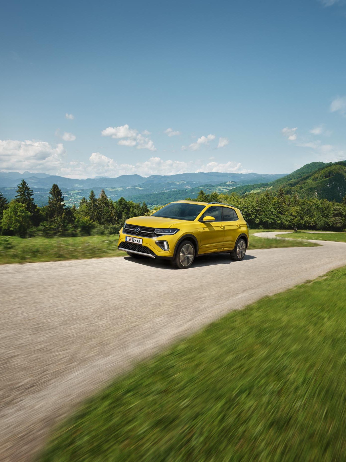 Žltý VW T-Cross na ceste v hornatej krajine.