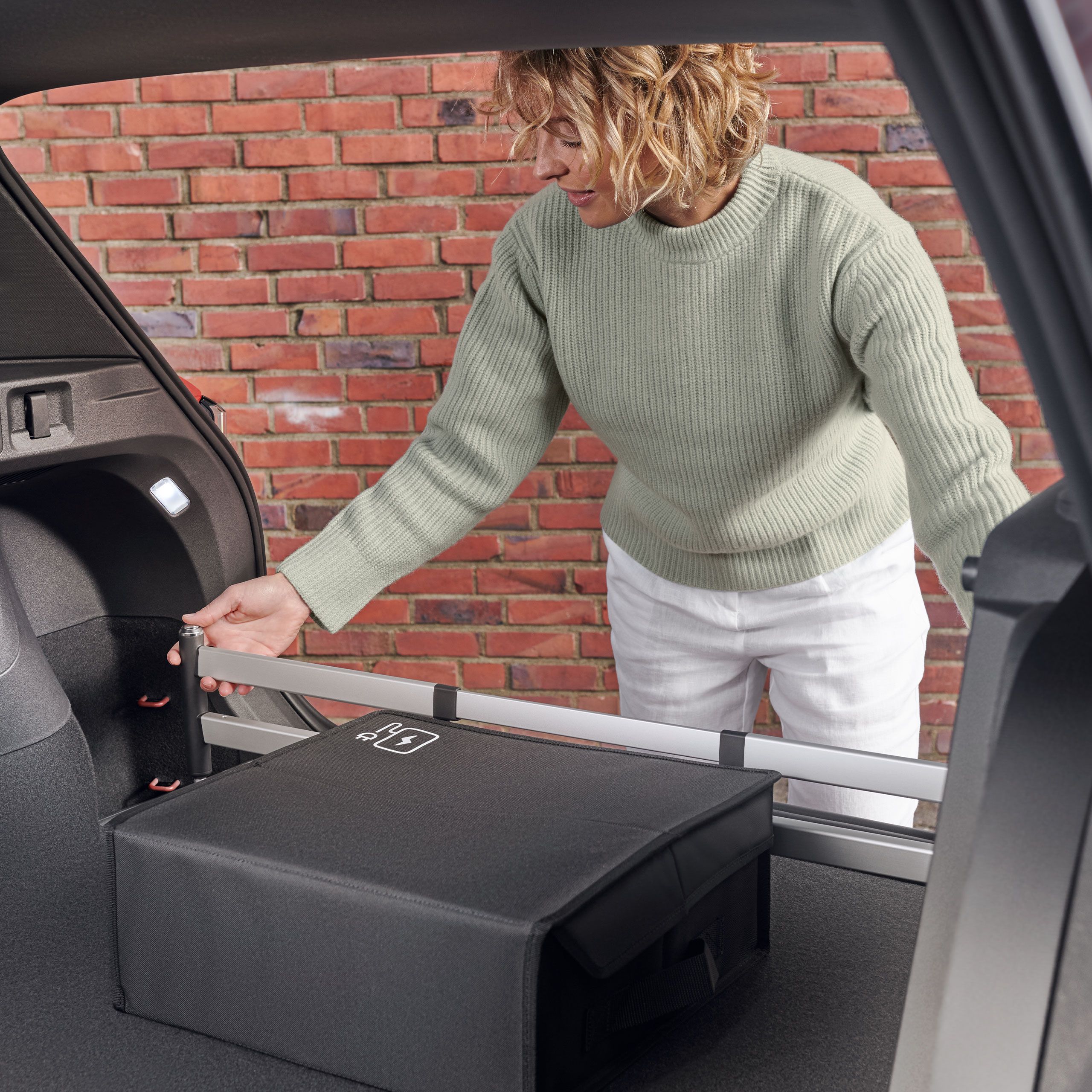 Žena montuje zásuvný modul do batožinového priestoru od VW do batožinového priestoru vozidla VW