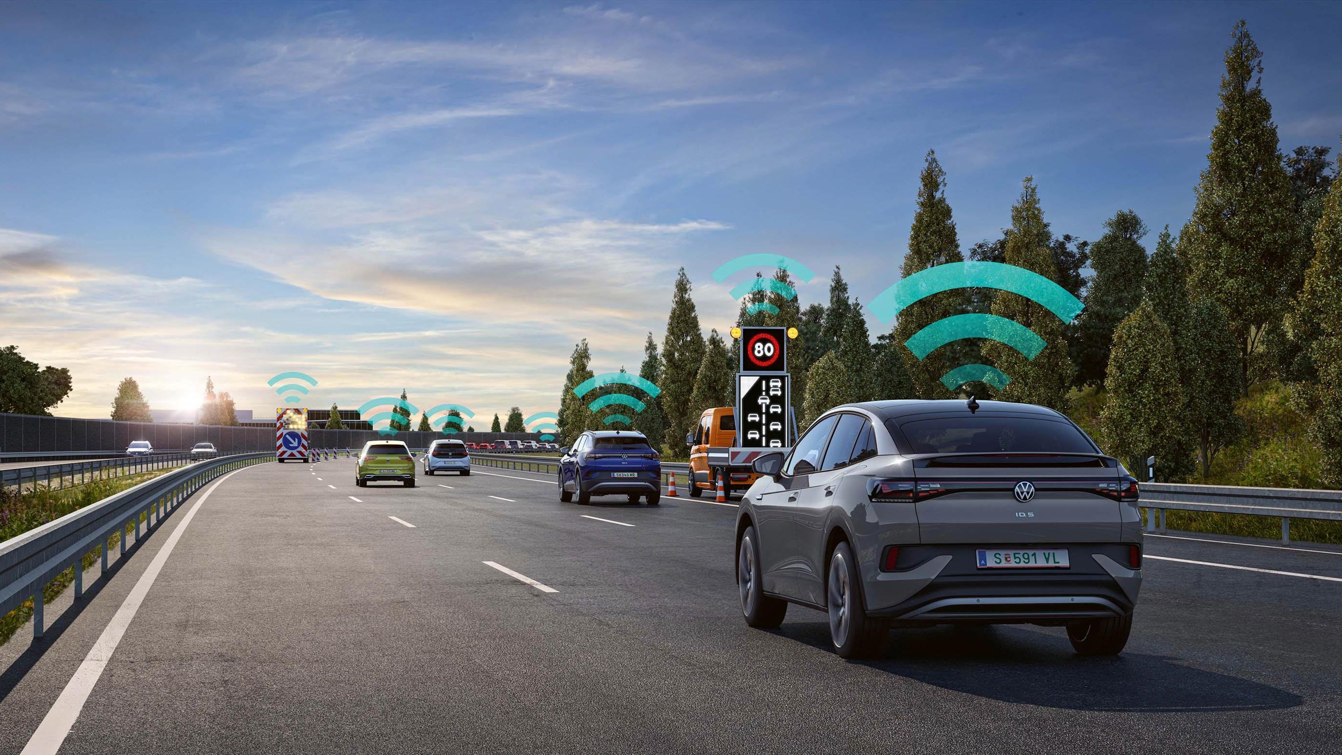 Niekoľko áut jazdí po diaľnici, pričom nad vozidlami je obrázok s vlnami zobrazujúci prenos bezdrôtového signálu. Na pravej strane cesty je elektronická značka s obmedzením rýchlosti. Na pozadí sú stromy a jasné nebo. Obrázok vysvetľuje fungovanie systému varovania pred nebezpečenstvom.