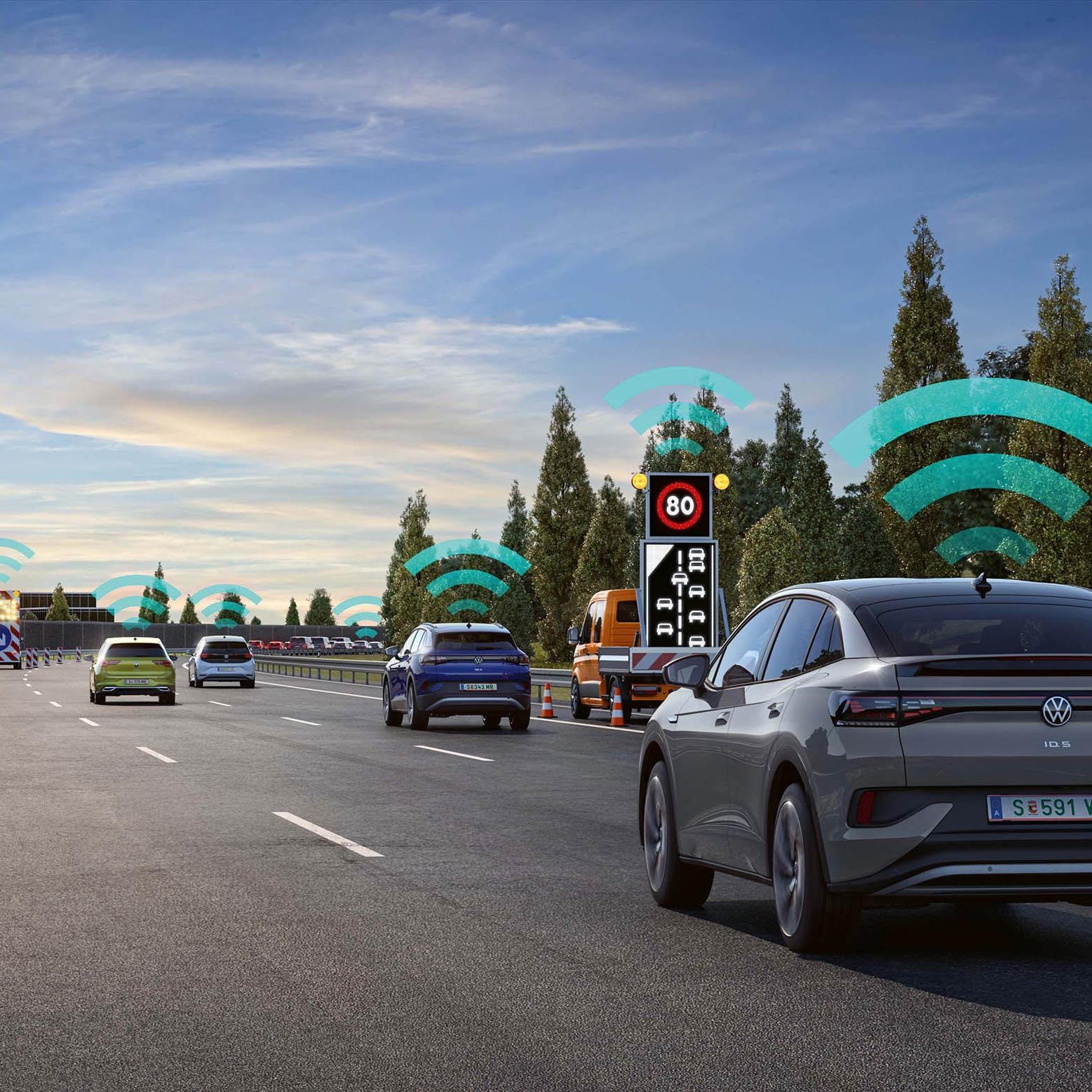 Niekoľko áut jazdí po diaľnici, pričom nad vozidlami je obrázok s vlnami zobrazujúci prenos bezdrôtového signálu. Na pravej strane cesty je elektronická značka s obmedzením rýchlosti. Na pozadí sú stromy a jasné nebo. Obrázok vysvetľuje fungovanie systému varovania pred nebezpečenstvom.