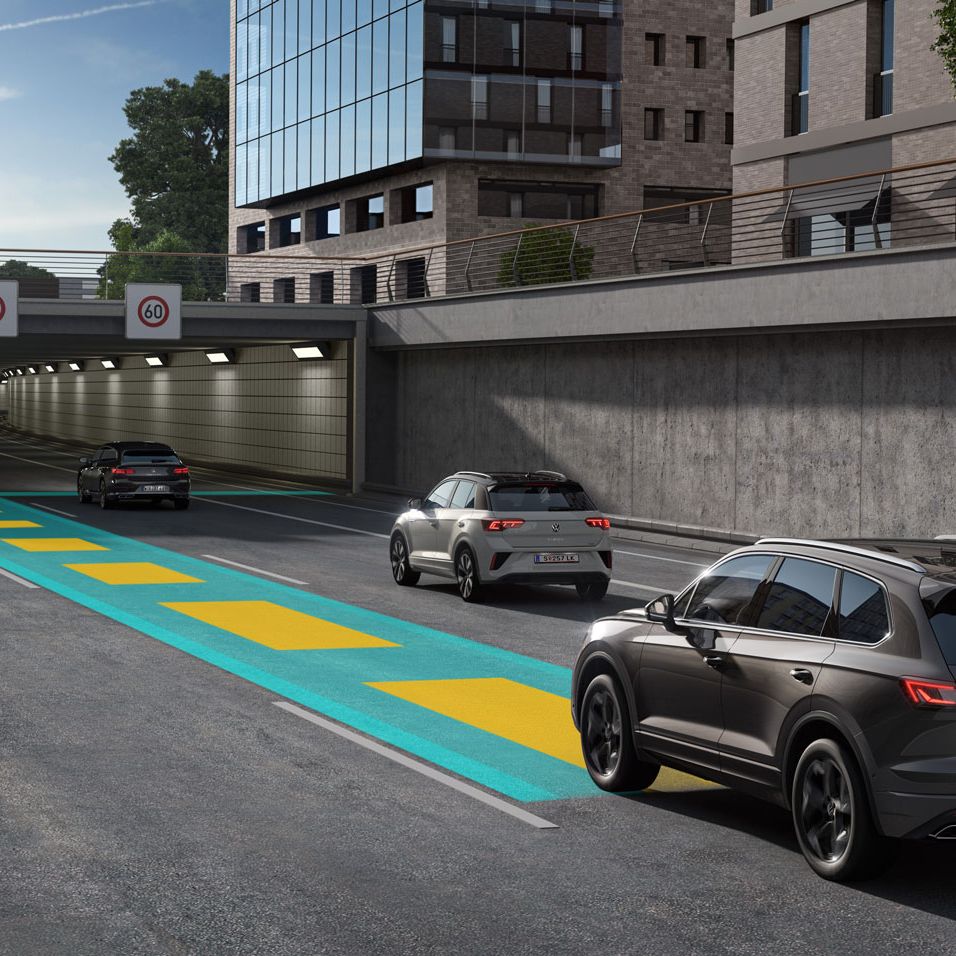 VW Volkswagen Touareg jazdí po diaľnici smerom do tunela. Grafika zobrazuje fungovanie systému Travel Assist.