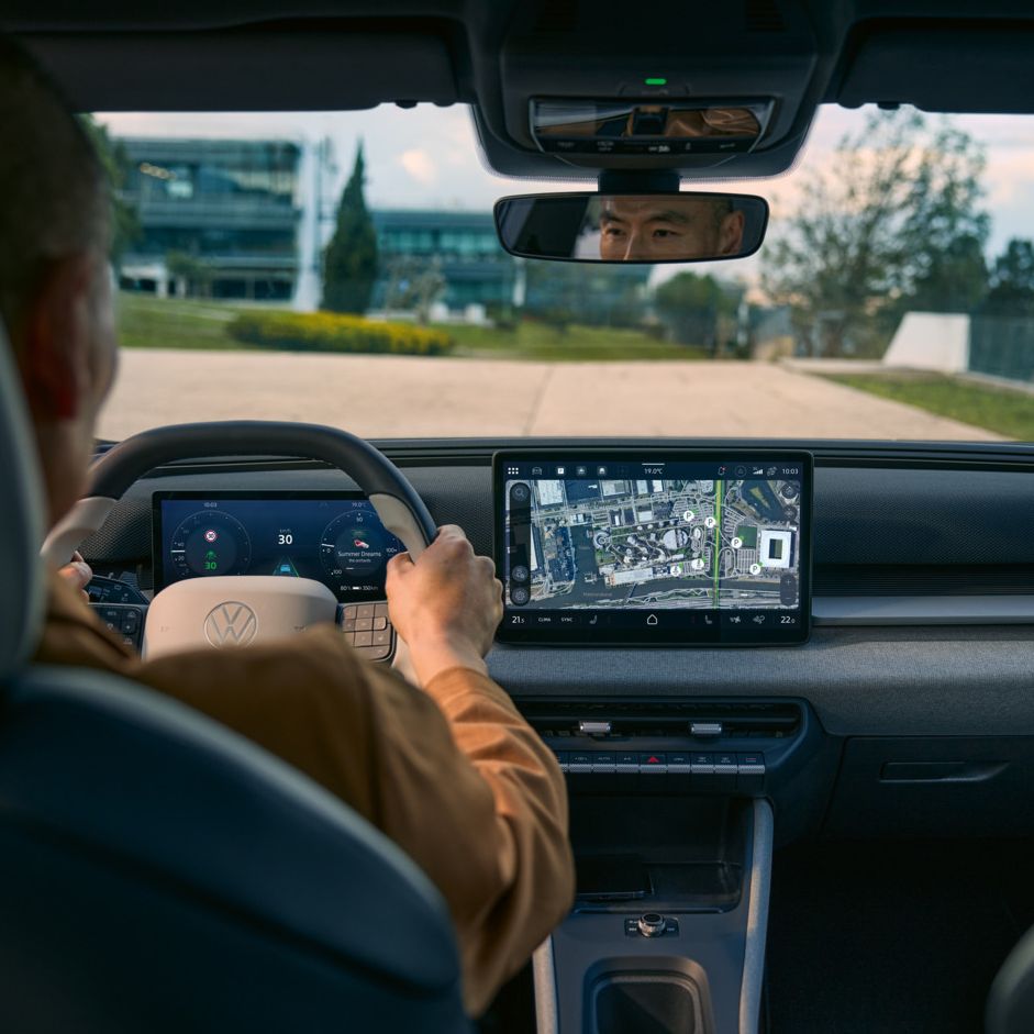 Pohľad zo zadného sedadla do kabíny vodiča na VW ID. Cross s aktívnou navigáciou na obrazovke systému infotainment.