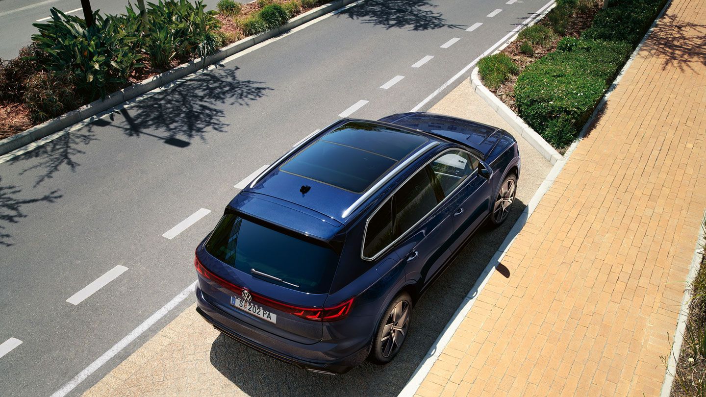 VW Volkswagen Touareg zaparkovaný na parkovacom mieste pri ceste a chodníku v meste.