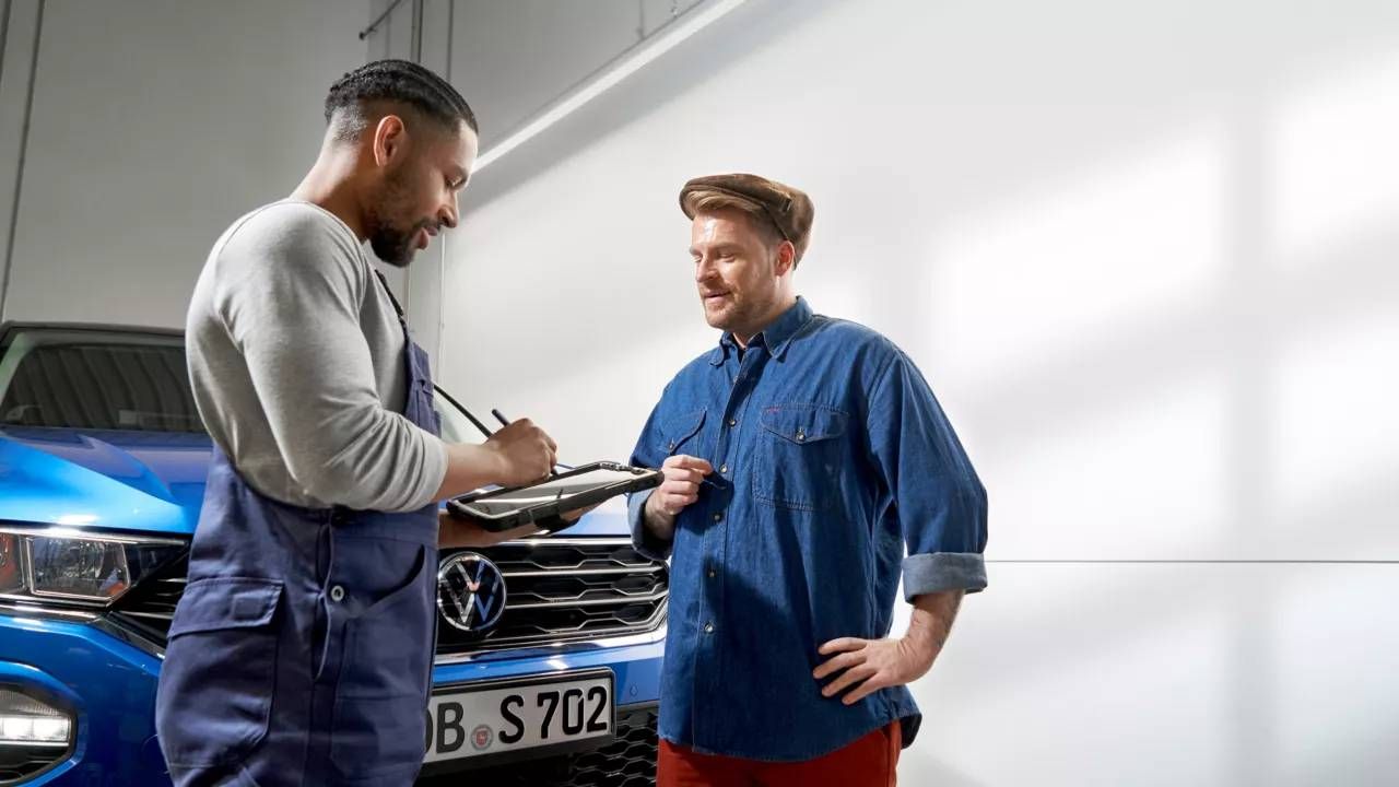 Zamestnanec v servise Volkswagen komunikuje so zákazníkom a zadáva informácie do tabletu.