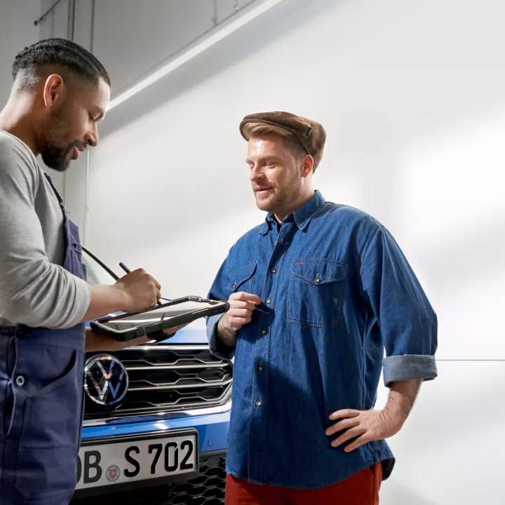 Zamestnanec v servise Volkswagen komunikuje so zákazníkom a zadáva informácie do tabletu.